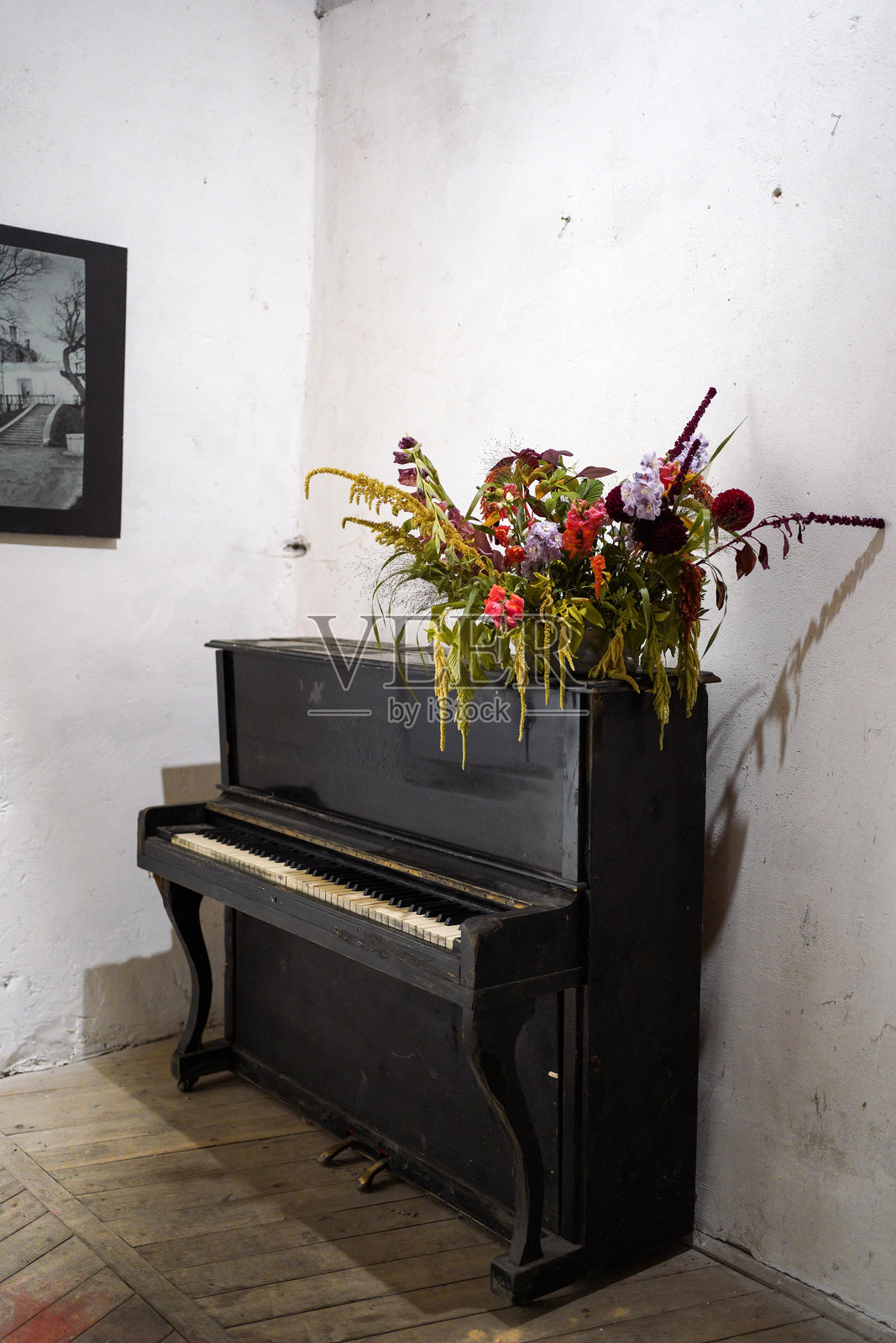 古老的立式钢琴上摆放着野花的花艺装饰，背景是乡村风格的室内环境照片摄影图片