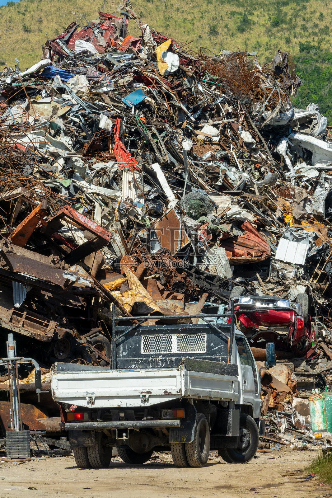 一辆卡车停在垃圾场的大堆废金属前，准备回收利用。照片摄影图片