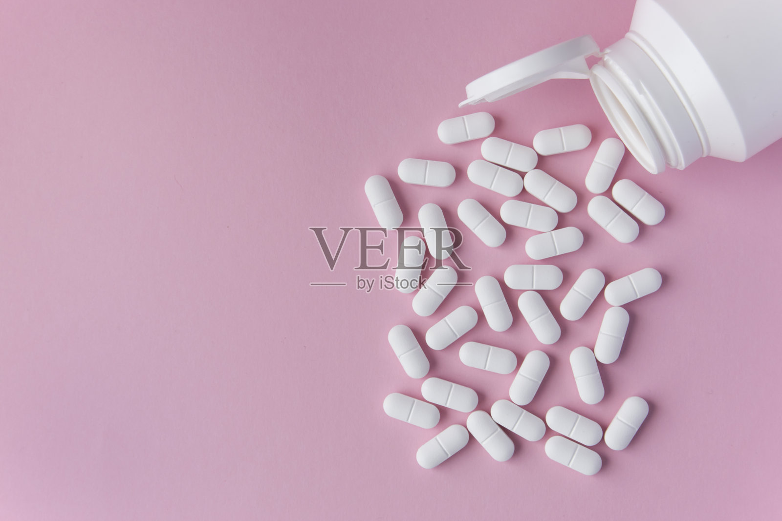 粉色背景上的白色药片或药丸，留有文字位置。照片摄影图片