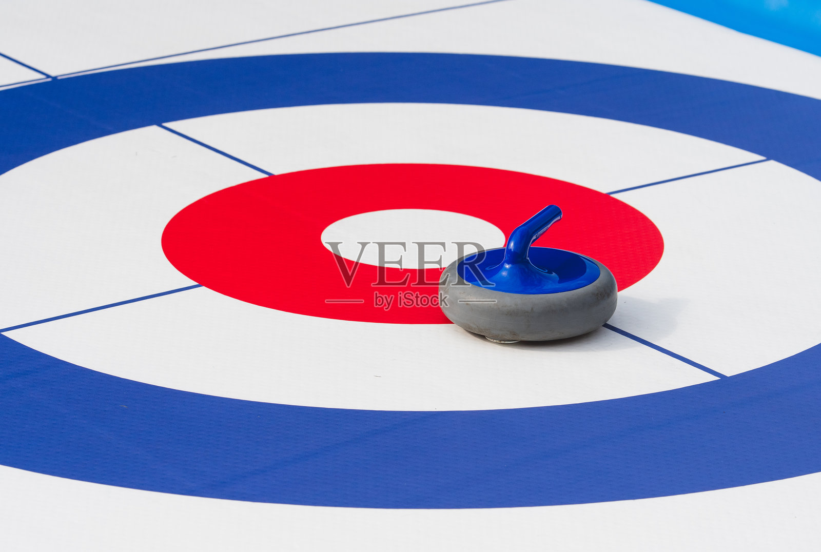 在标记的比赛场地上，冰壶石放置在冰壶靶心或房子的中心。照片摄影图片