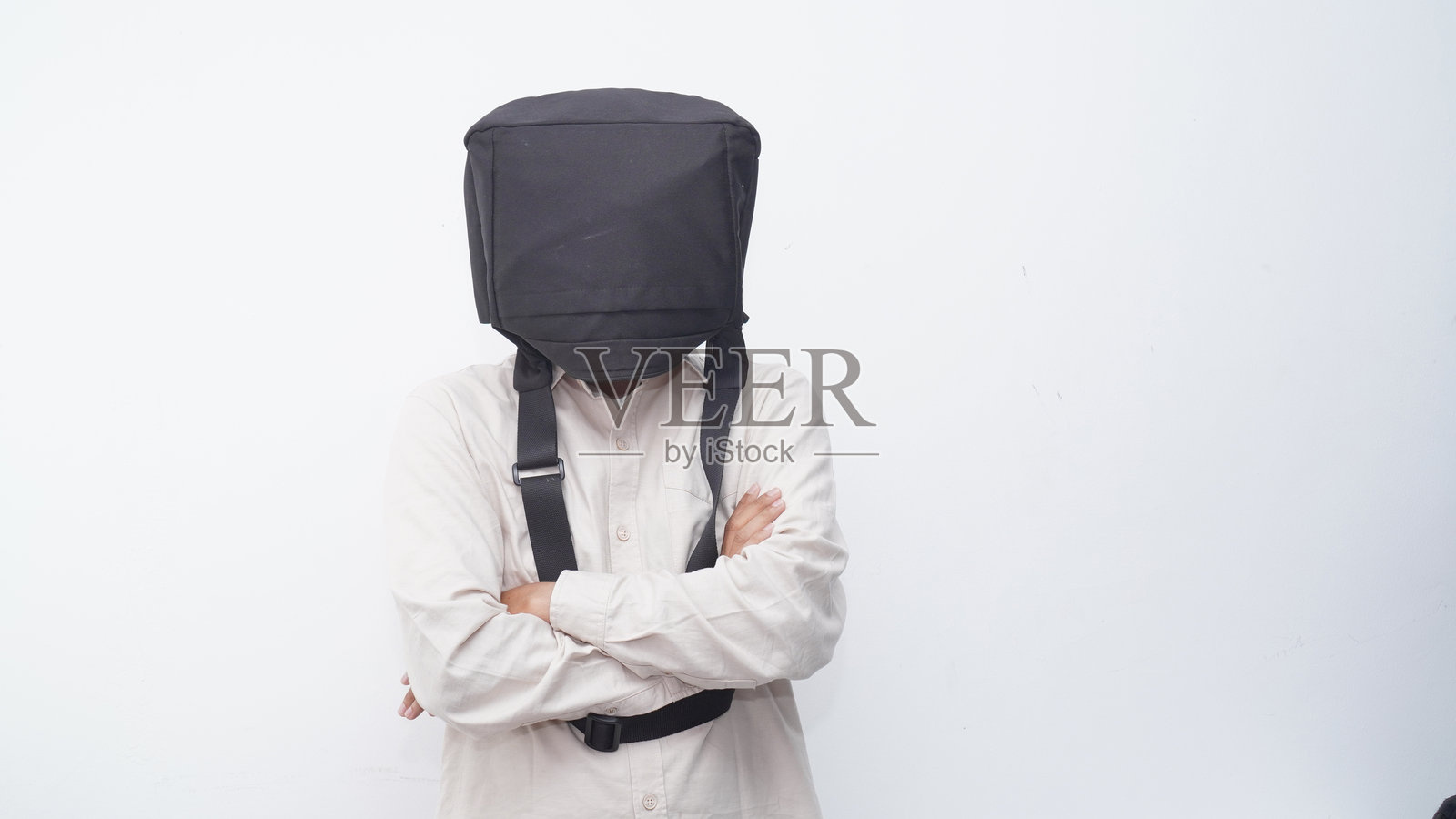 商人用黑色斜挎包遮住头部，背景为白色。照片摄影图片