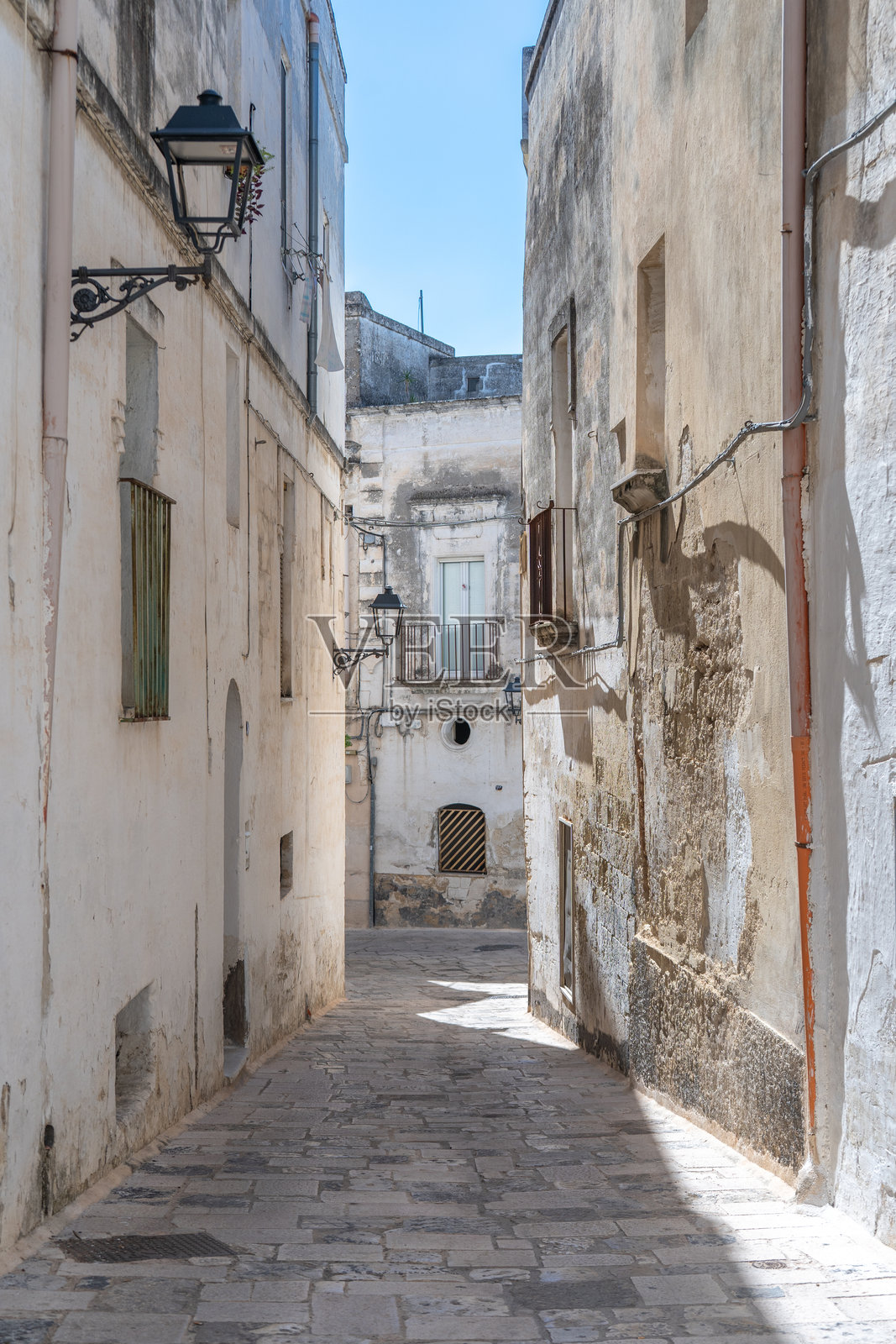 意大利格罗塔利，2025年9月7日。历史中心的石头小巷和地中海阳台之间的建筑在蓝天下的景象，南意大利。格罗塔利是一座陶瓷之城。照片摄影图片