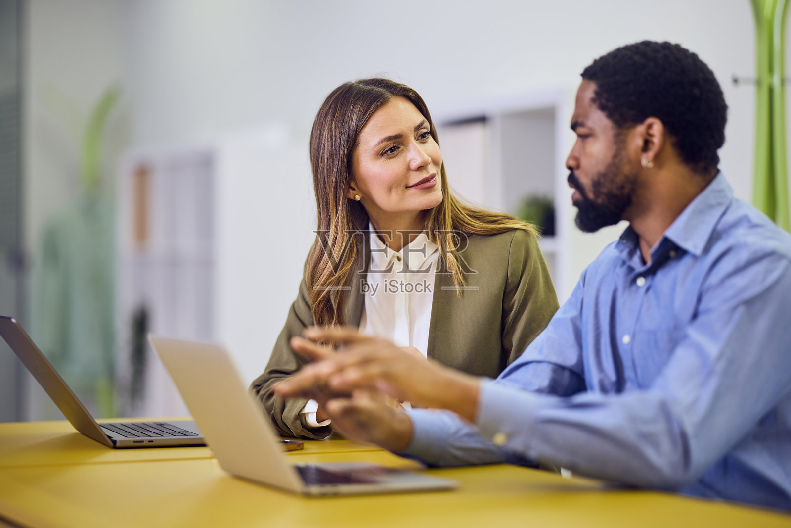 两位同事在现代专业办公室环境中协作使用笔记本电脑照片摄影图片