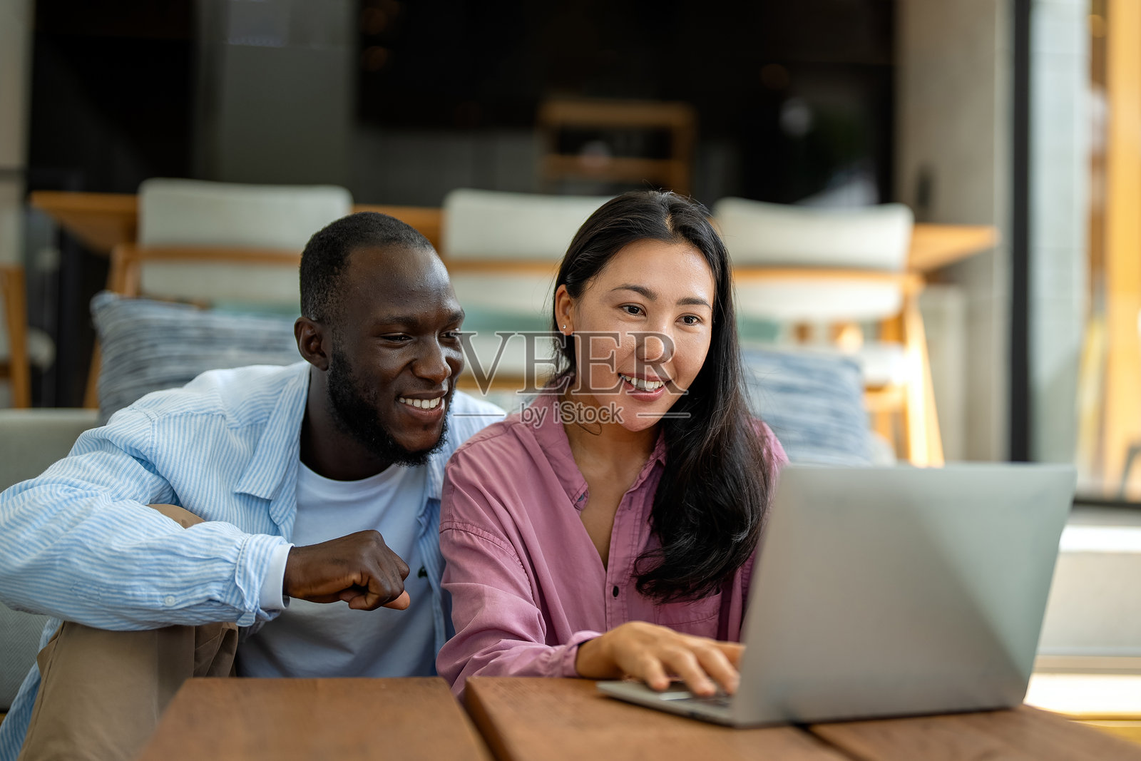 快乐的黑人和亚洲夫妇一起使用笔记本电脑，微笑的妻子和丈夫在网上购物照片摄影图片