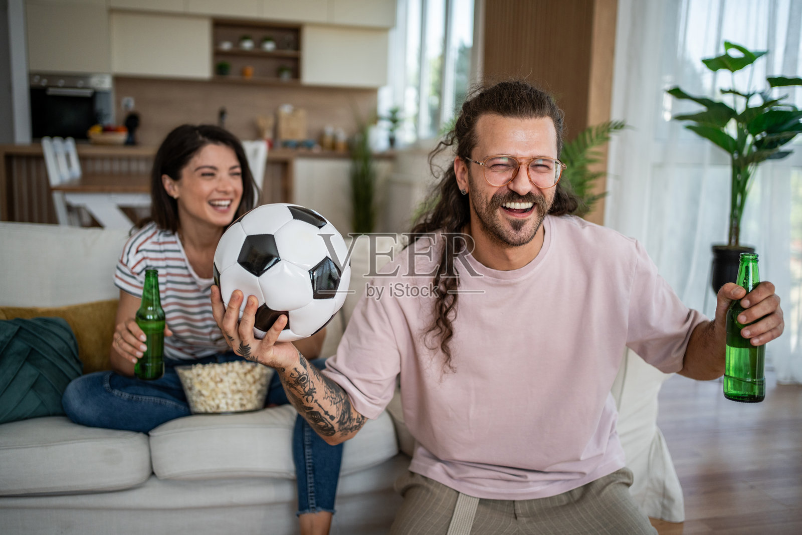 一对情侣在看电视时喝啤酒，享受足球比赛的乐趣照片摄影图片