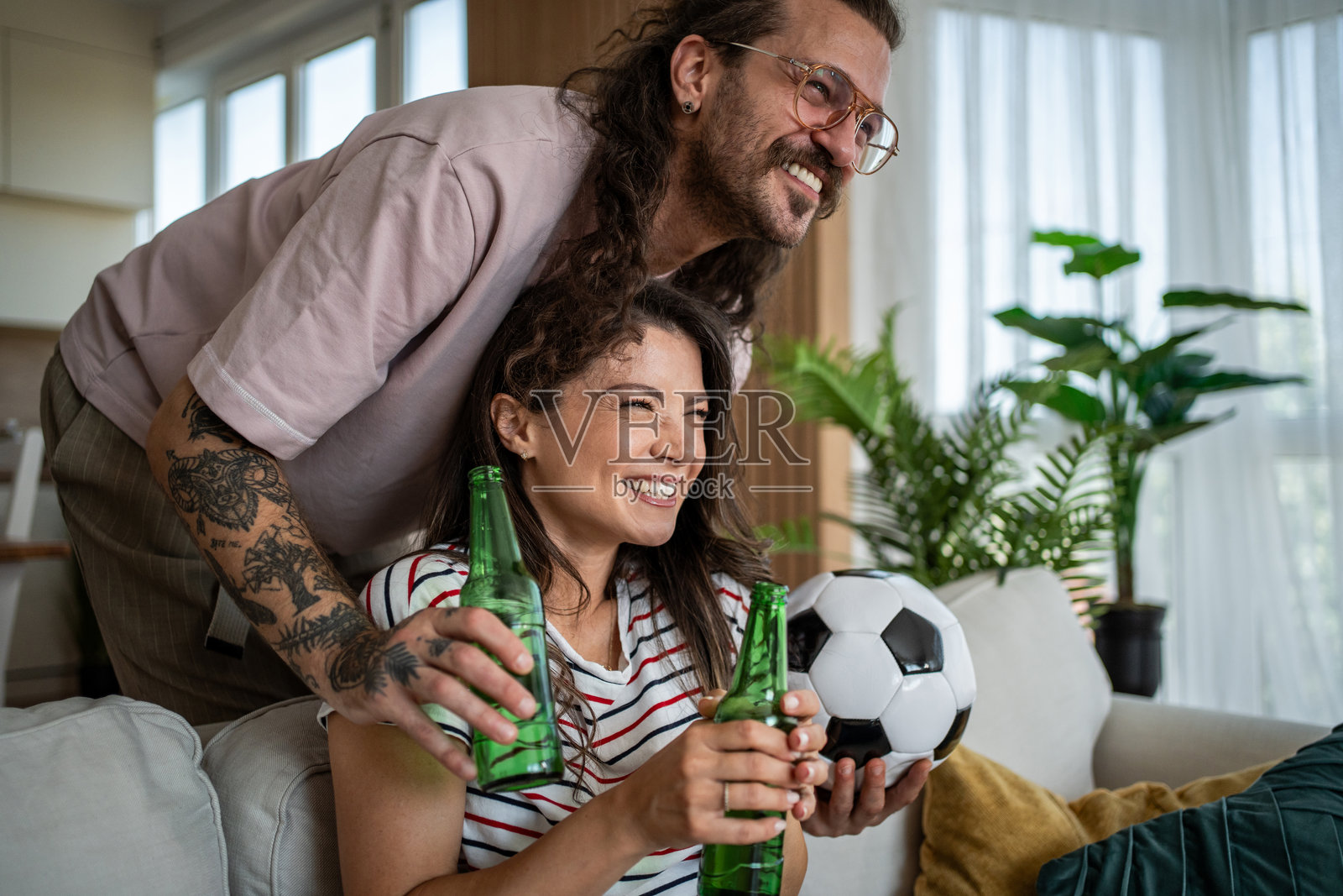 一对情侣在看电视比赛时喝啤酒并拿着足球照片摄影图片