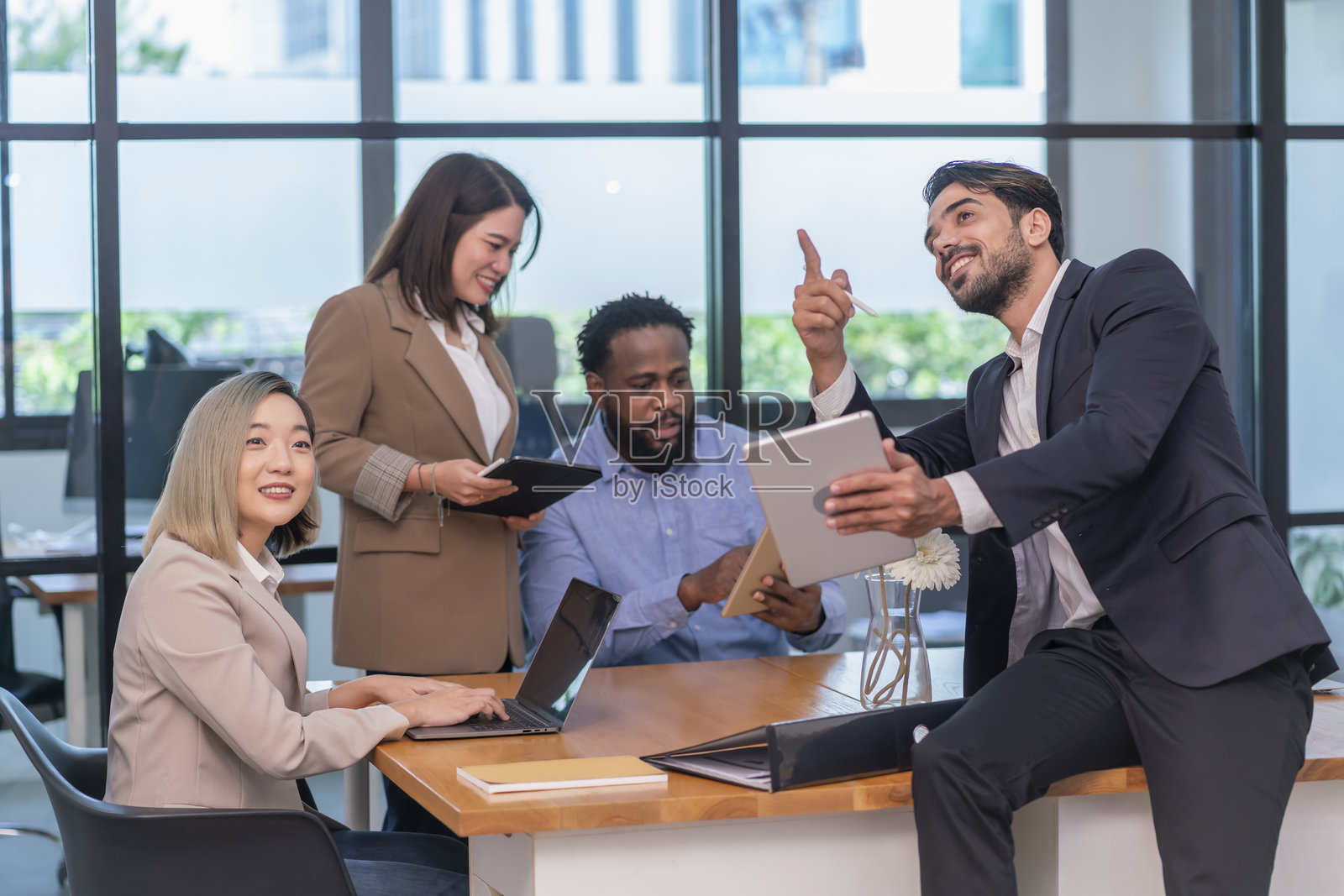 商业公司办公室工作，多种族员工在办公室内工作，开会，讨论使用笔记本电脑、平板电脑和文件。照片摄影图片