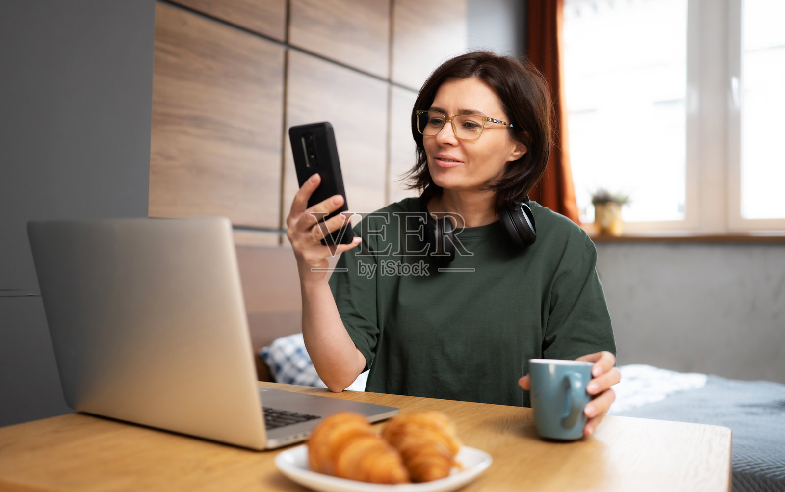 漂亮的女性使用智能手机并与笔记本电脑工作照片摄影图片