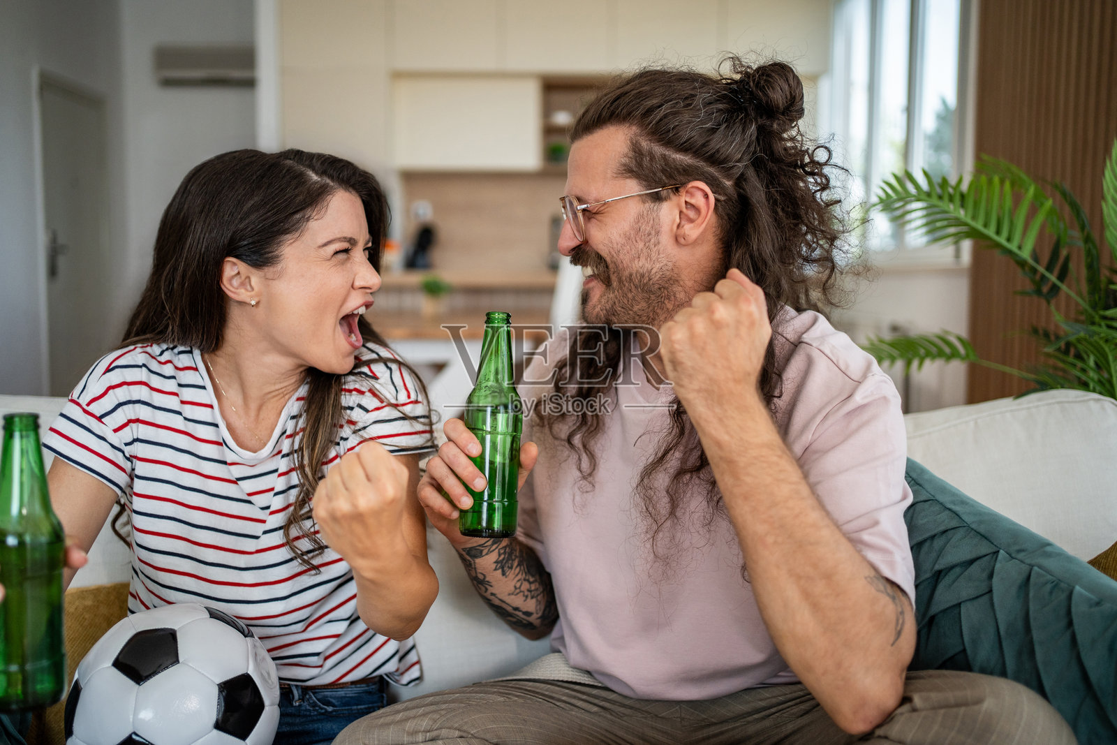 兴奋的情侣在家观看足球比赛时欢呼照片摄影图片
