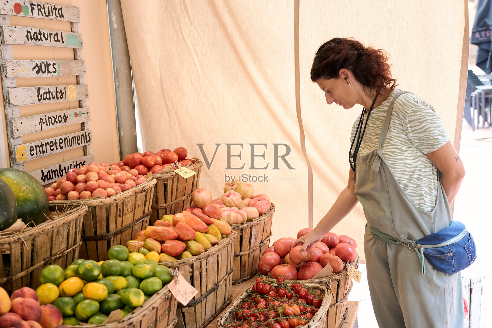 女性在农贸市场的摊位上挑选石榴，展示新鲜农产品 - 经济危机与通货膨胀照片摄影图片