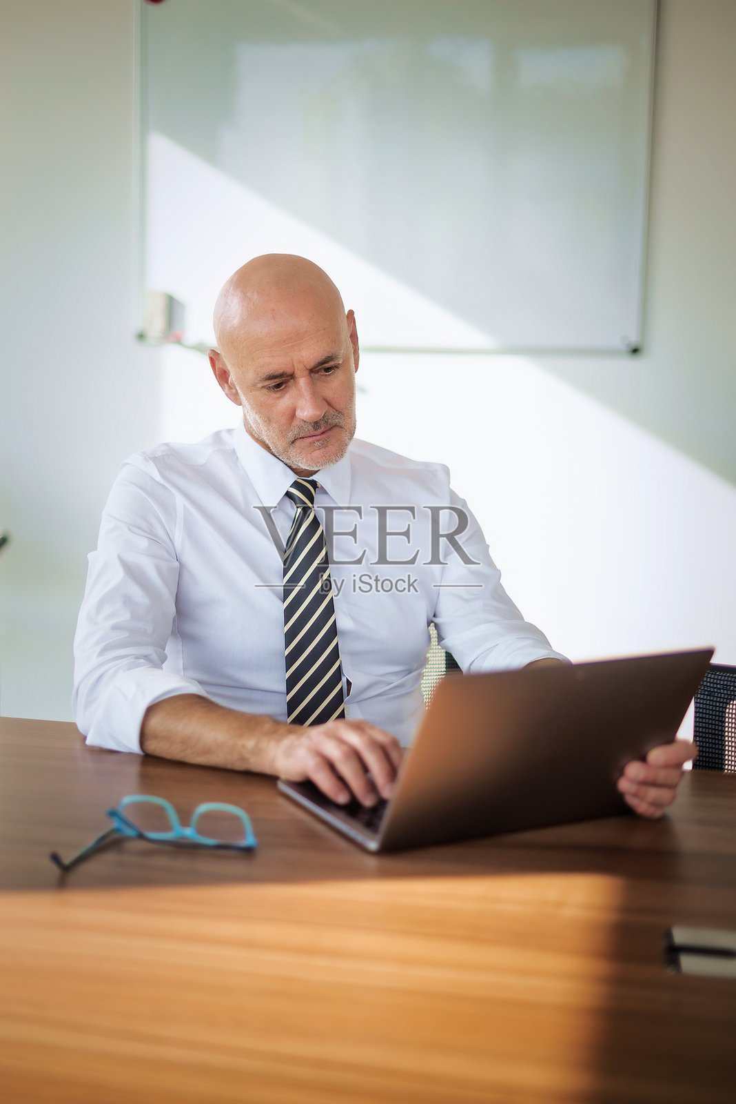 中年商人在现代办公室的办公桌前使用笔记本电脑照片摄影图片