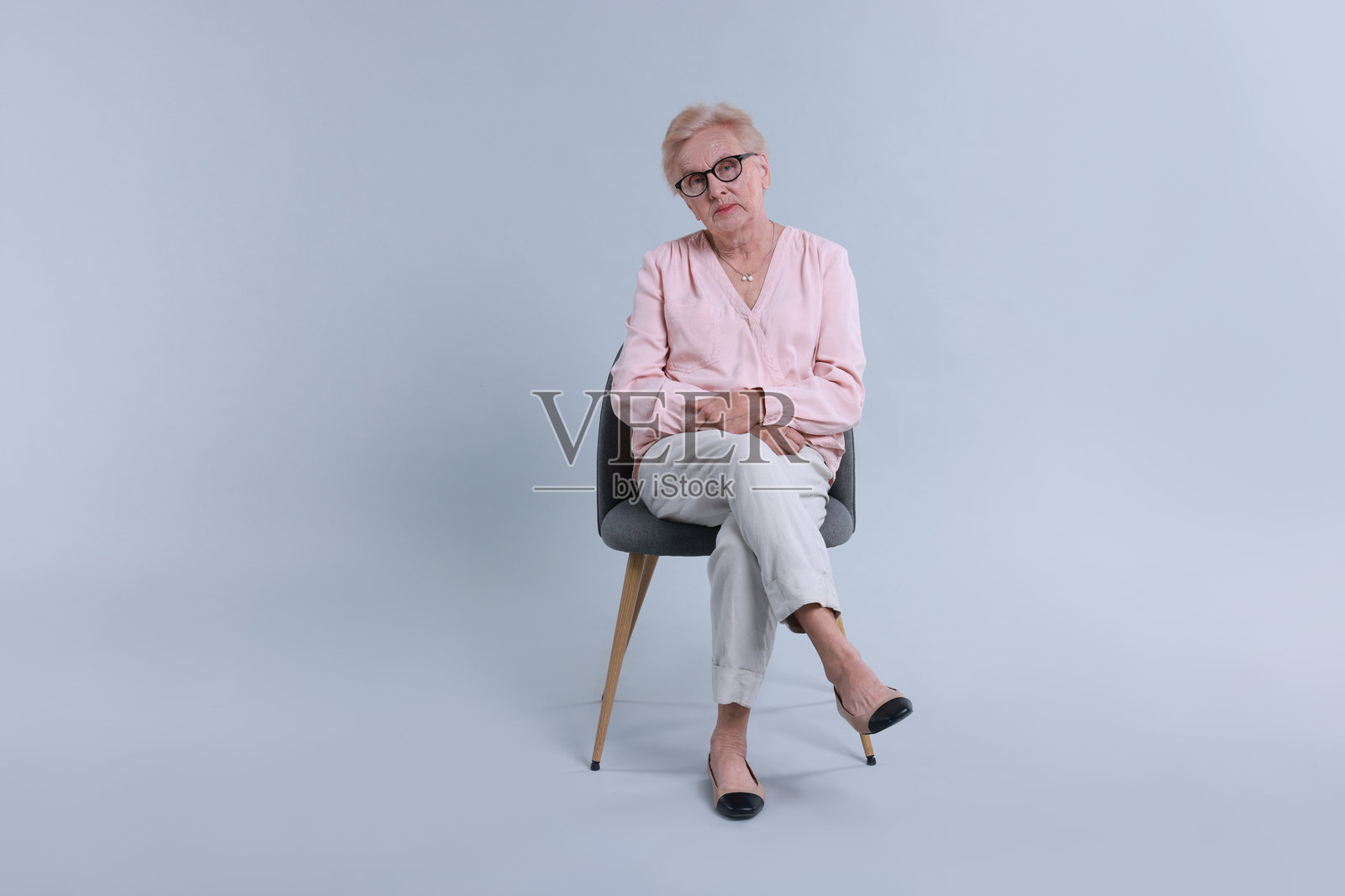 坐在椅子上的老年女性，背景明亮照片摄影图片
