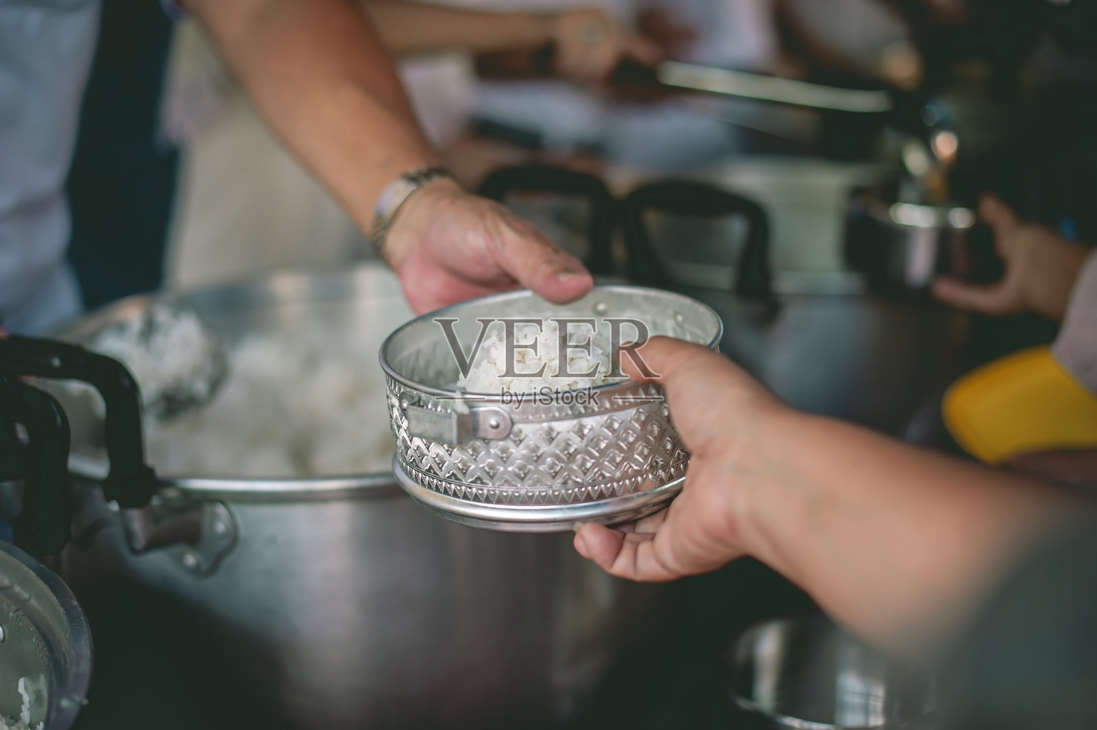 将食物馈赠给乞讨者，体现贫困和慈善的概念，贫困者的手从施予者的份额中接收食物。照片摄影图片