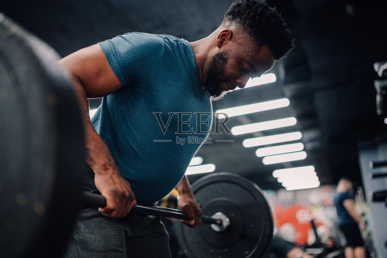 年轻的健美运动员在健身房举重照片摄影图片