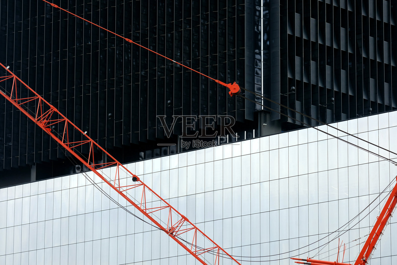 一只起重机正站在一栋建筑前。照片摄影图片