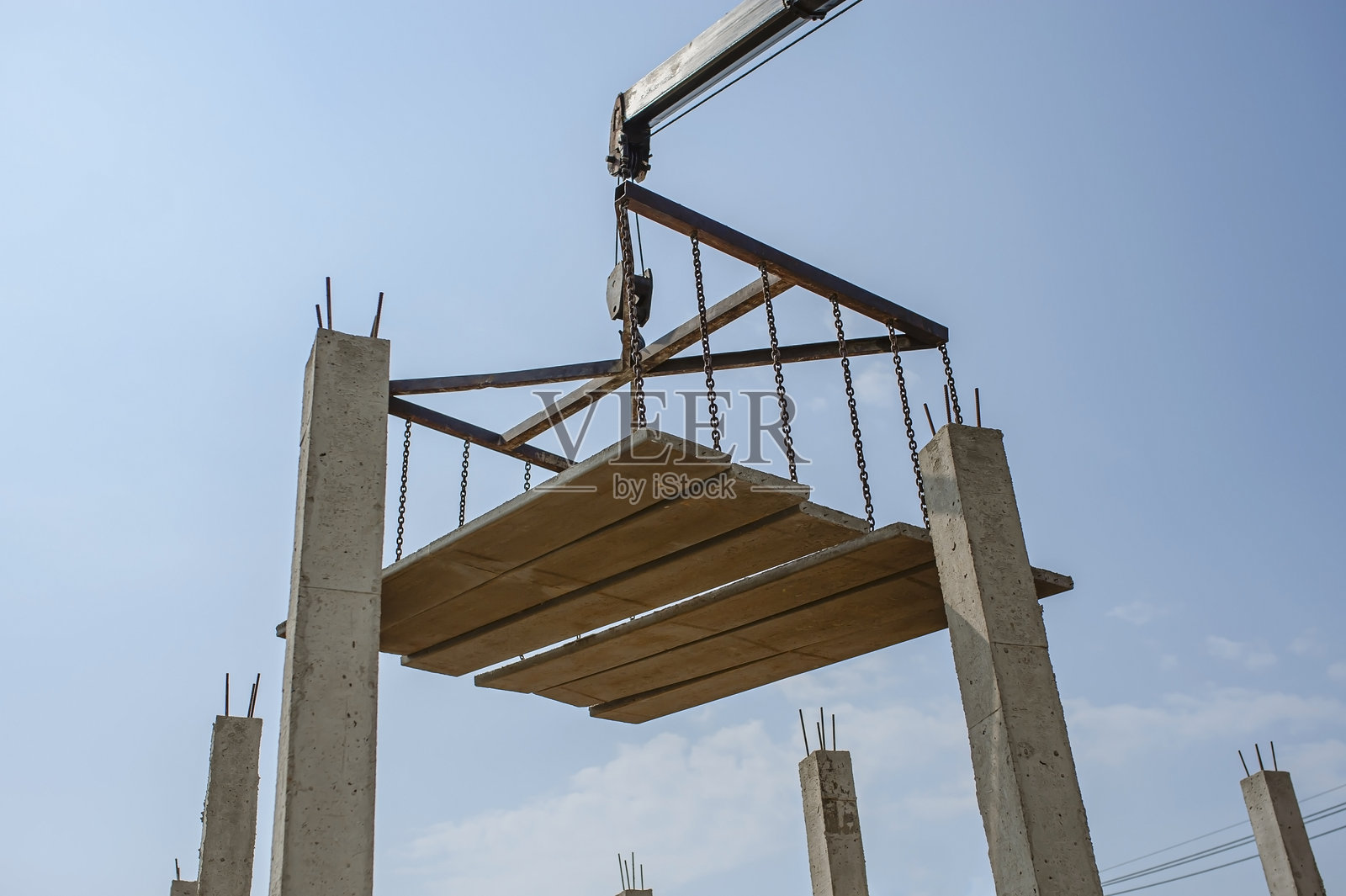 机器的臂部在建筑施工中提升地板板块。照片摄影图片