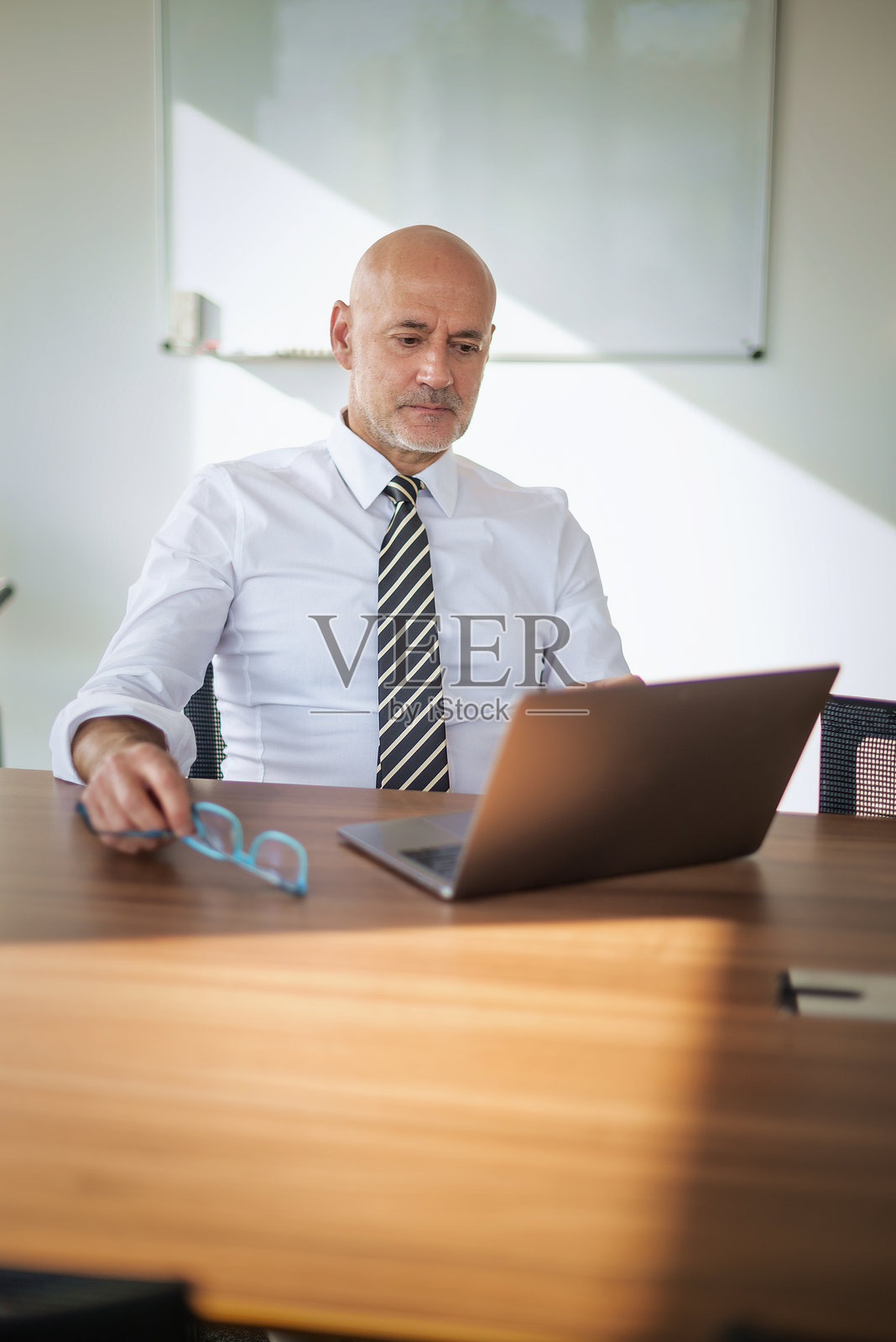 中年商人在现代办公室的办公桌前使用笔记本电脑照片摄影图片