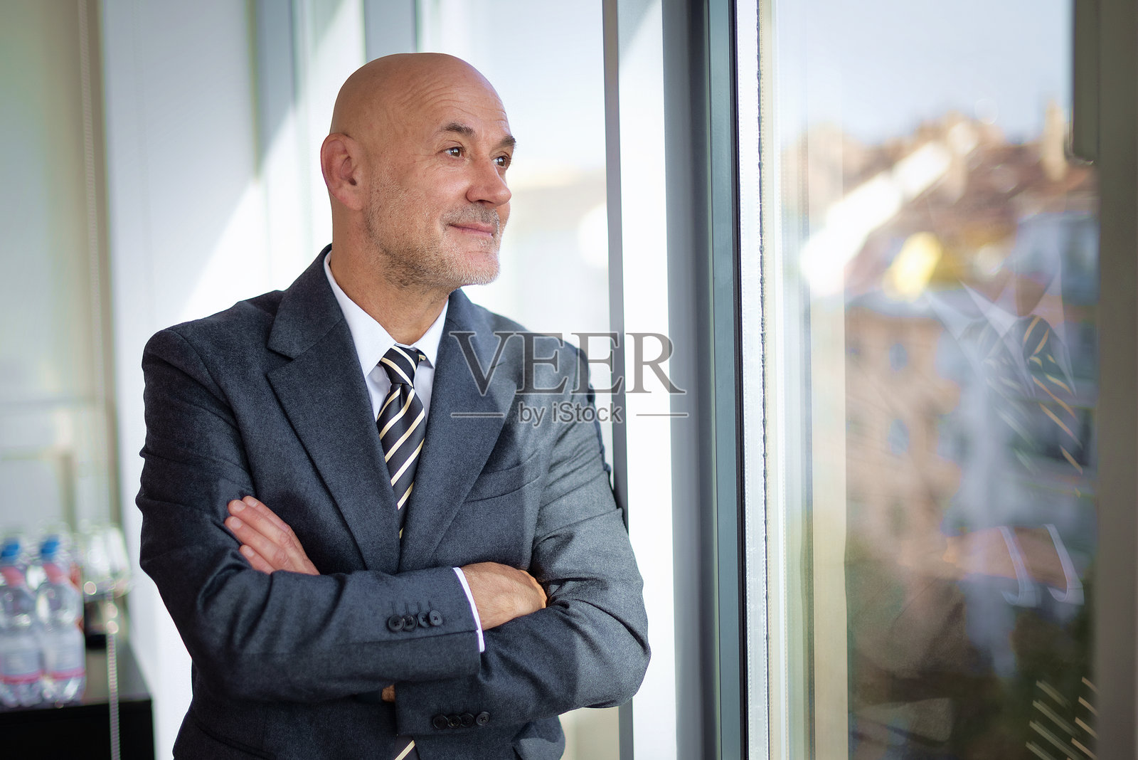 自信的高级商务人士站在现代办公室的窗边照片摄影图片