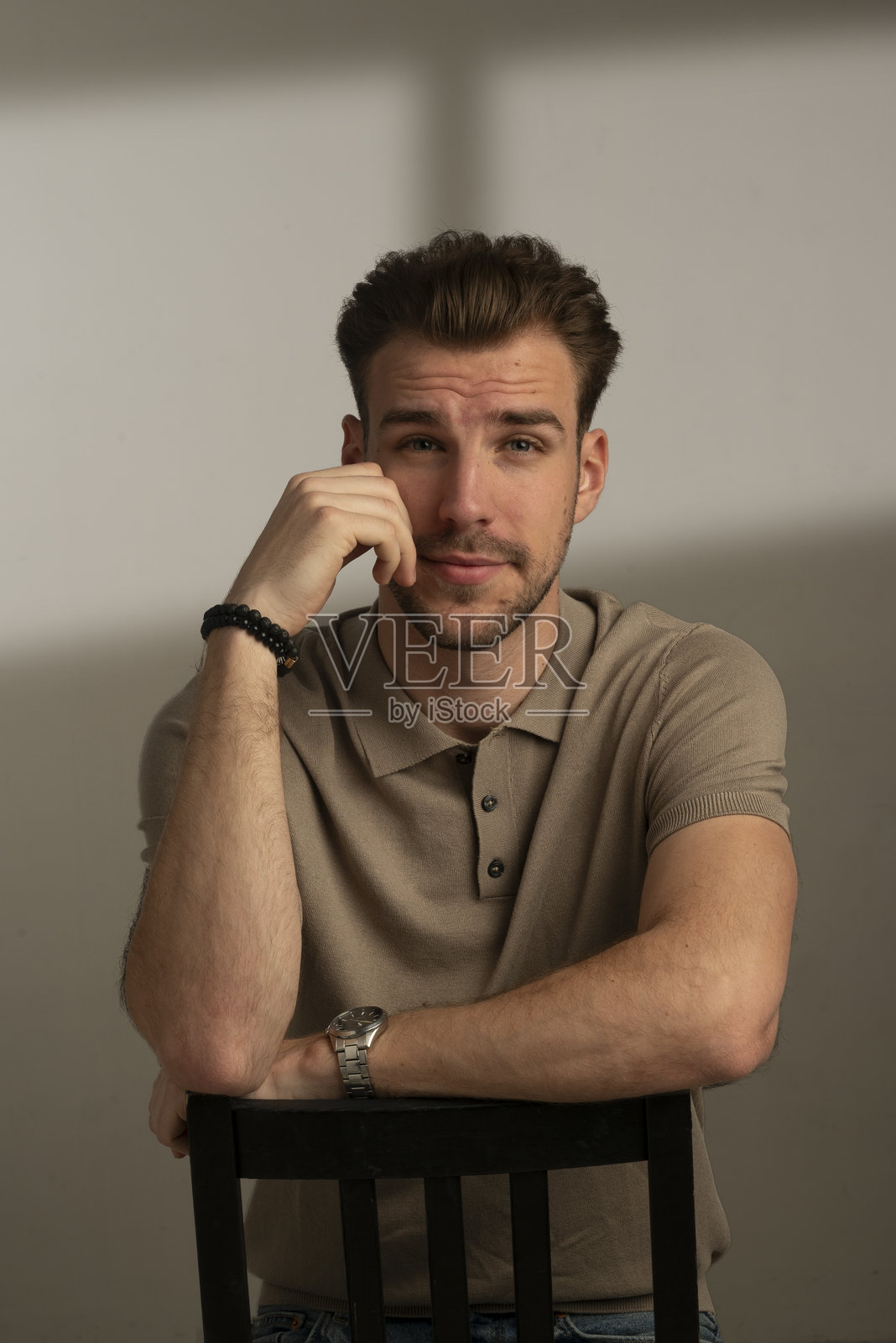 一位英俊年轻男子坐在孤立背景前的肖像照片摄影图片