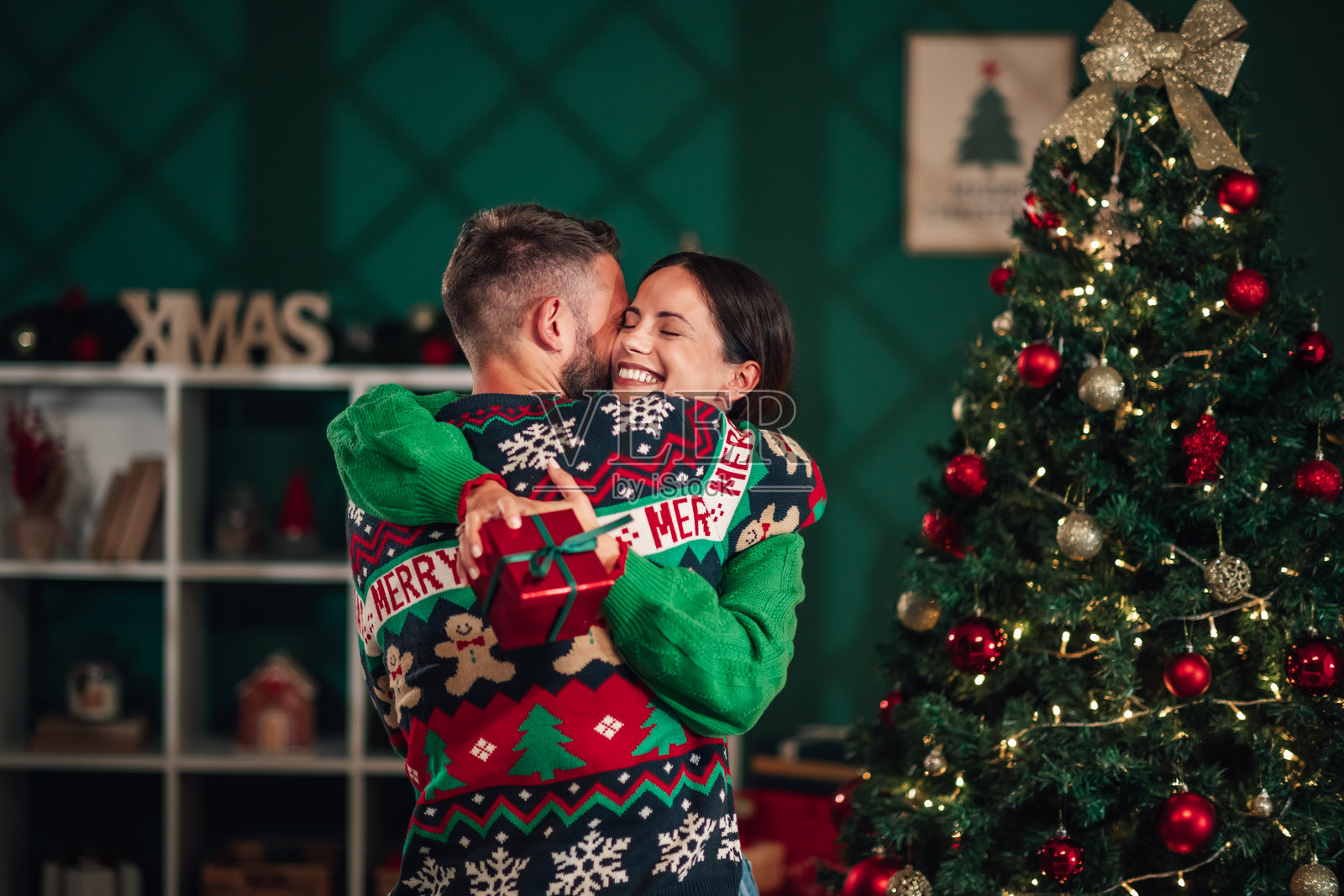 情侣在家中互赠圣诞礼物并相拥而抱照片摄影图片