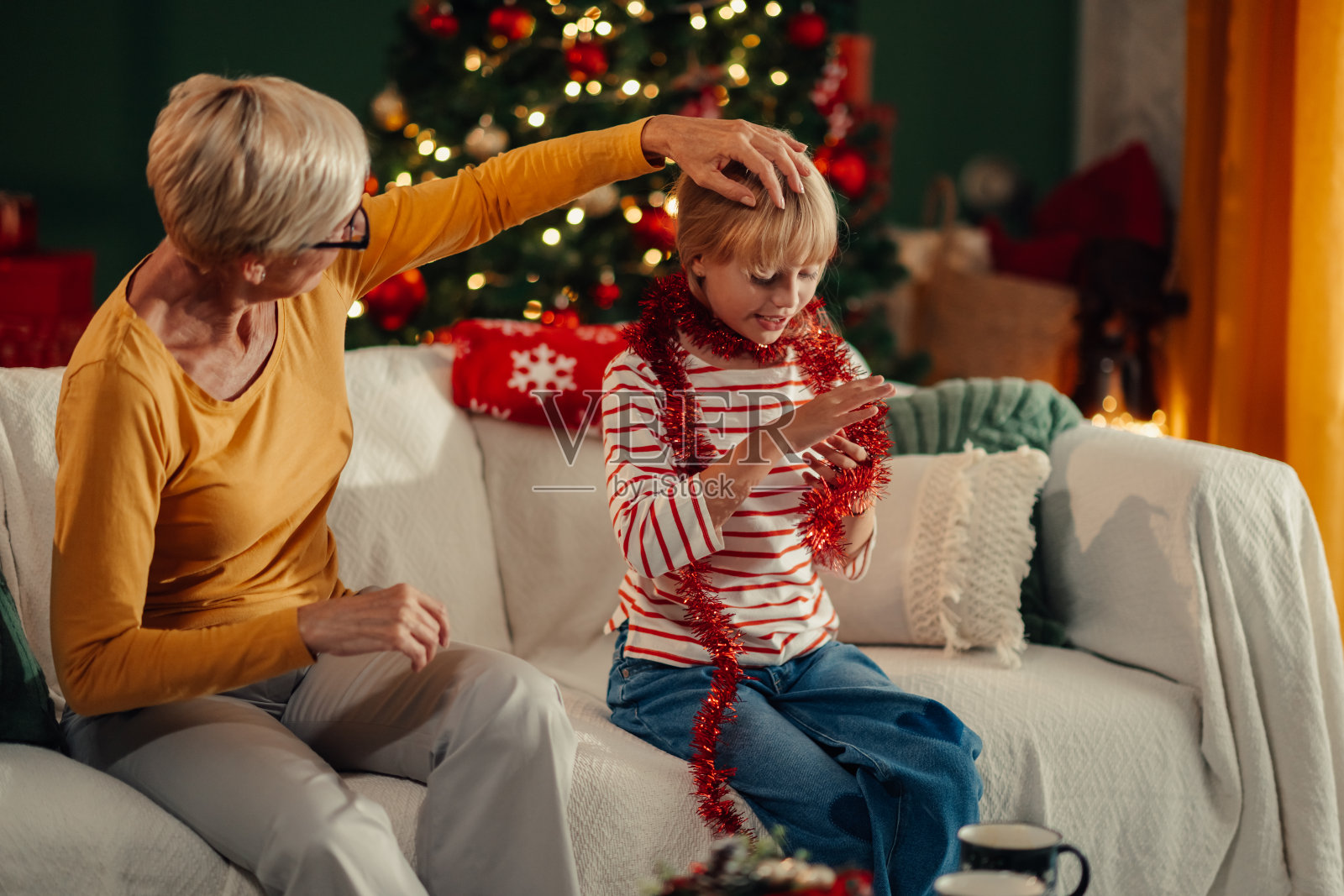 祖母在玩圣诞装饰时抚摸孙女照片摄影图片