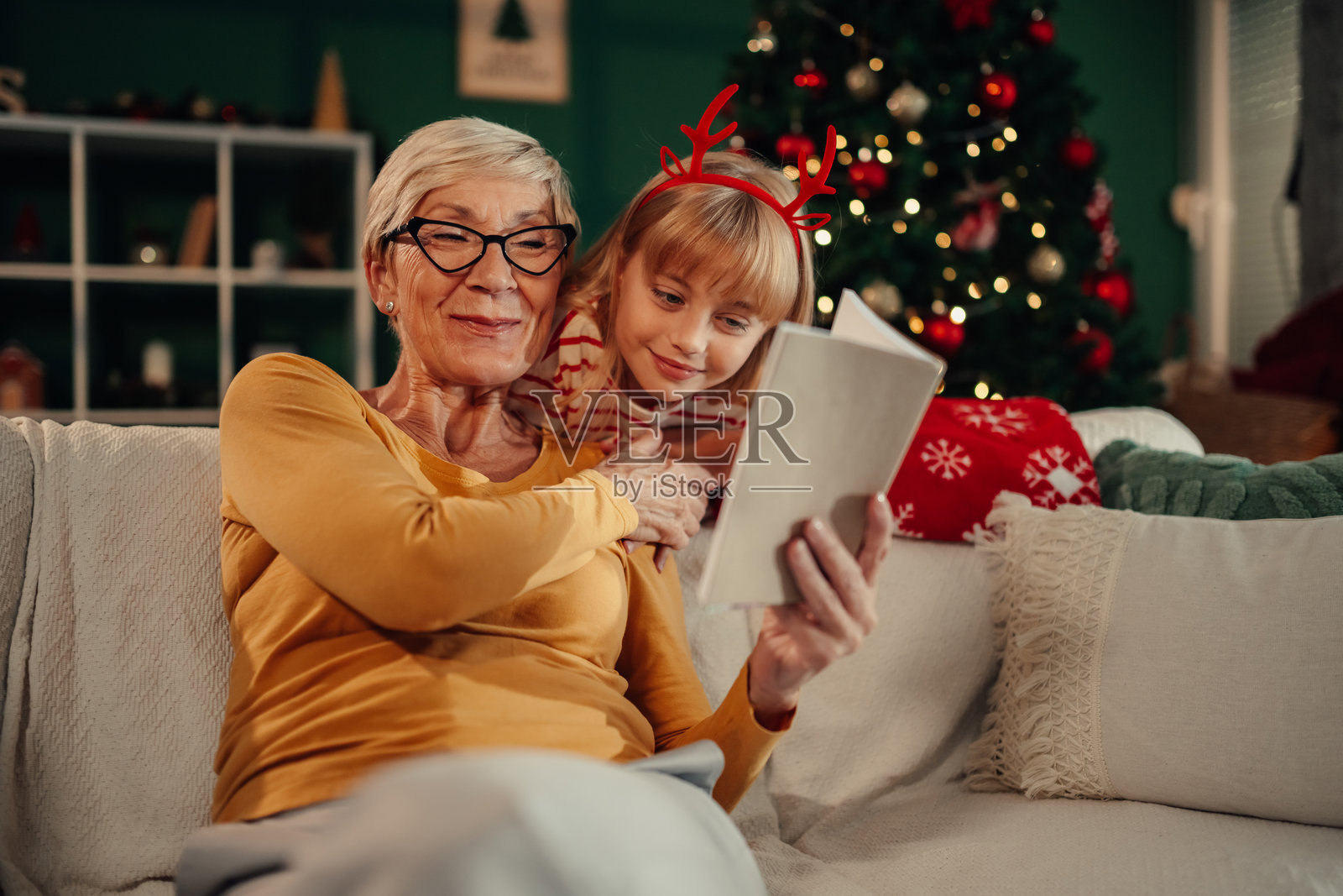 祖母在沙发上给孙女讲圣诞故事照片摄影图片