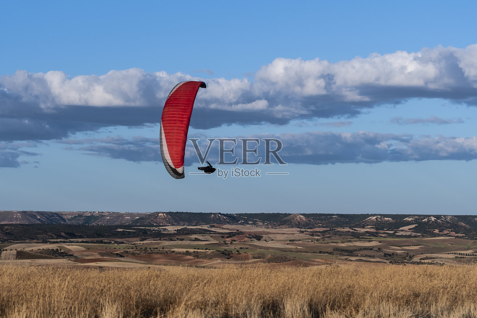 滑翔伞在金色时光下的蓝天中飞翔，俯瞰起伏的山丘照片摄影图片