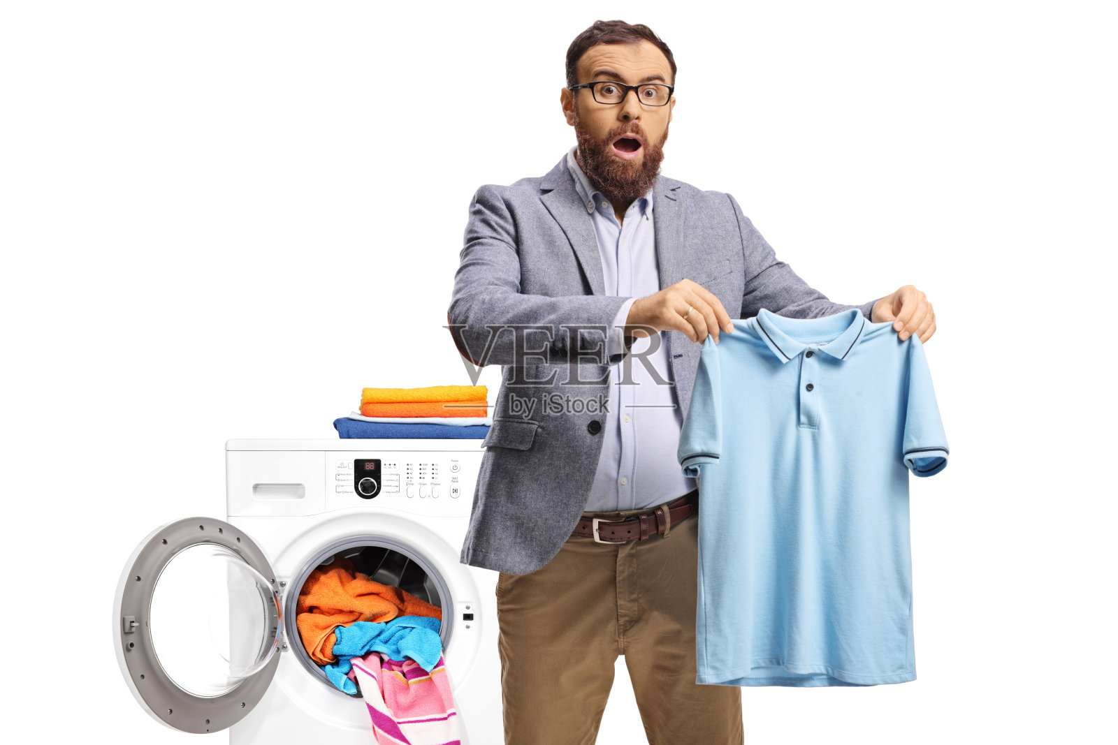 惊讶的男人在洗衣机前拿着一件小T恤照片摄影图片