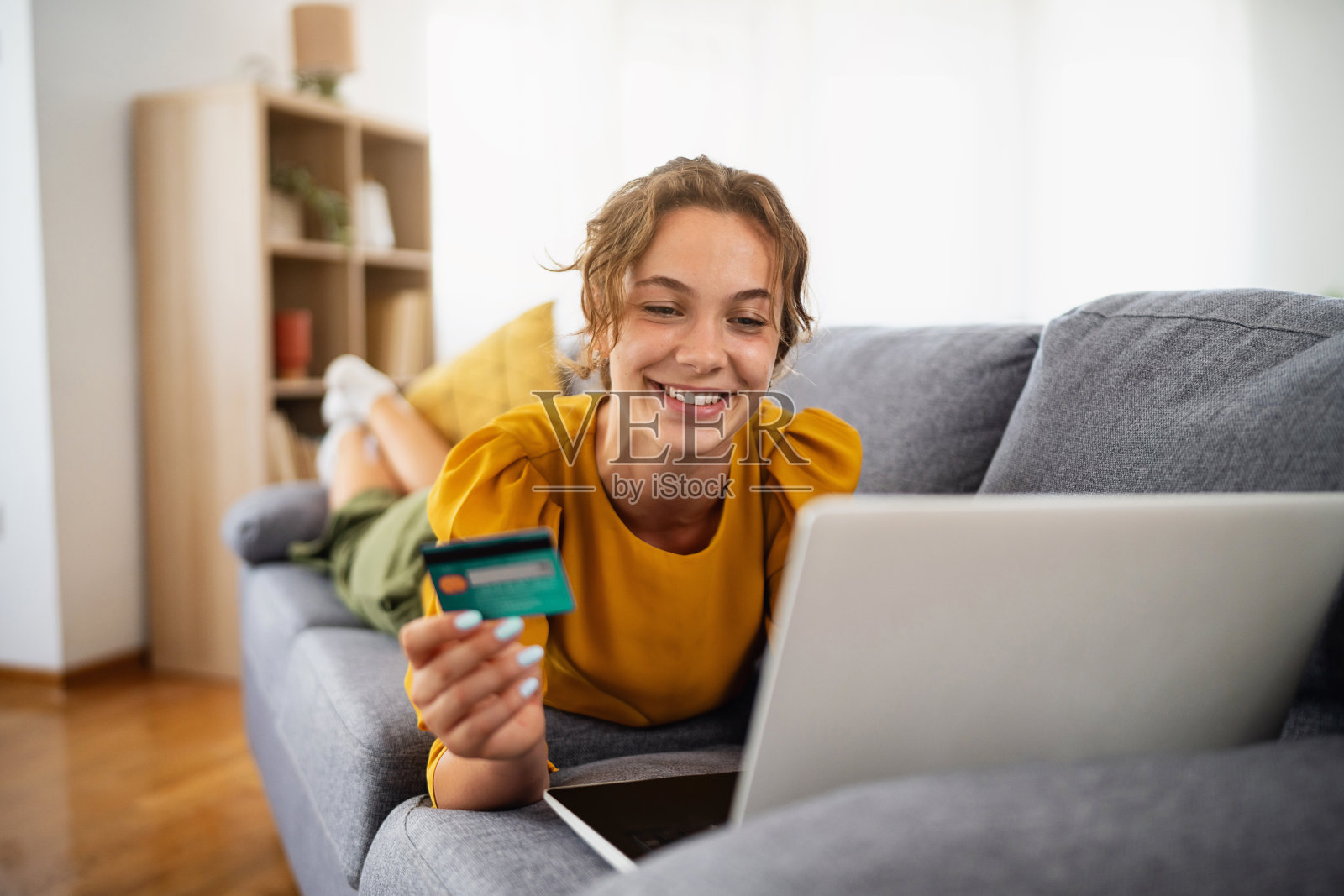 年轻女性在沙发上用信用卡进行网上购物照片摄影图片