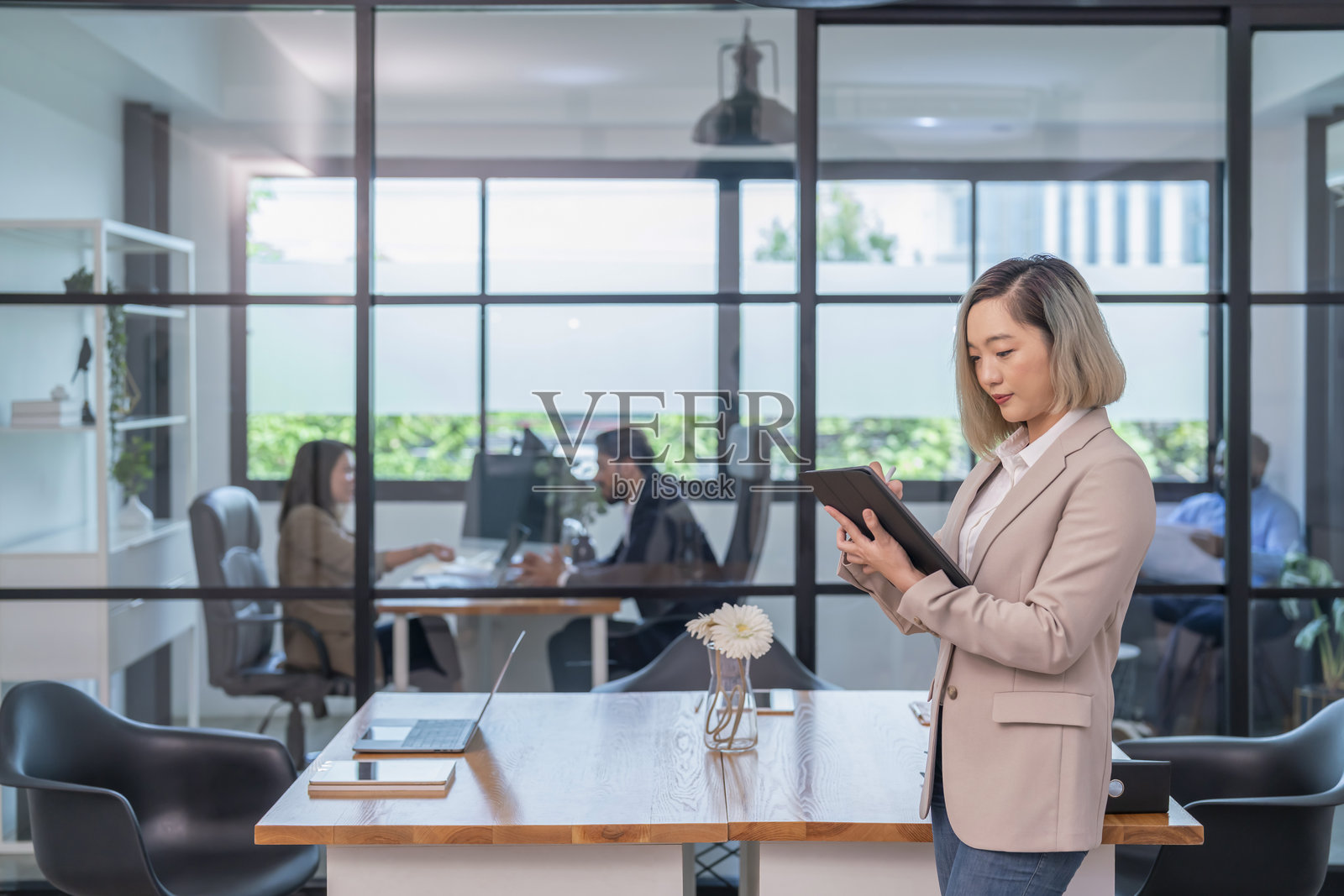 亚洲女性公司员工在工作场所的桌子上使用平板电脑工作，商务员工在办公室工作照片摄影图片