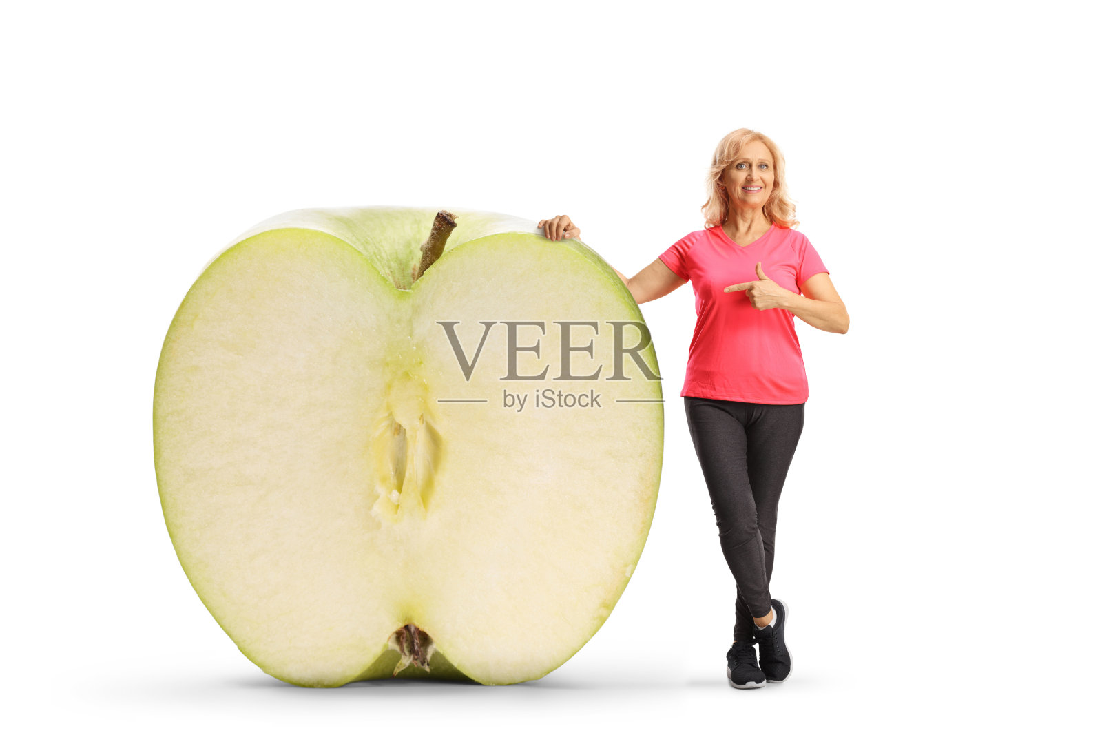 中年女性穿着运动服，指着一个大绿色苹果照片摄影图片