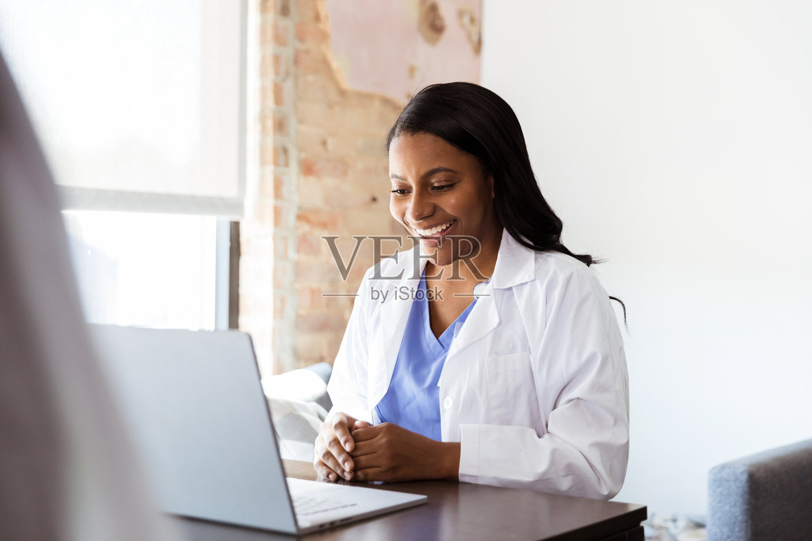 微笑的女医生使用笔记本电脑进行远程医疗咨询照片摄影图片