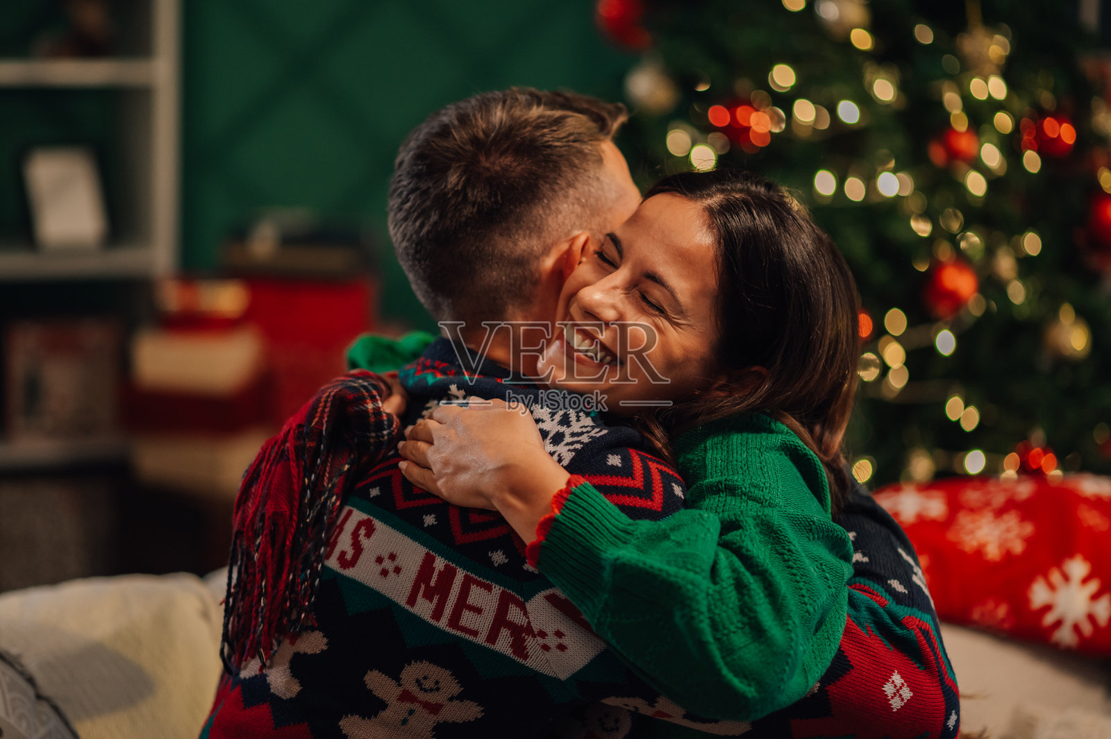 快乐的情侣在家中拥抱，庆祝圣诞假期照片摄影图片
