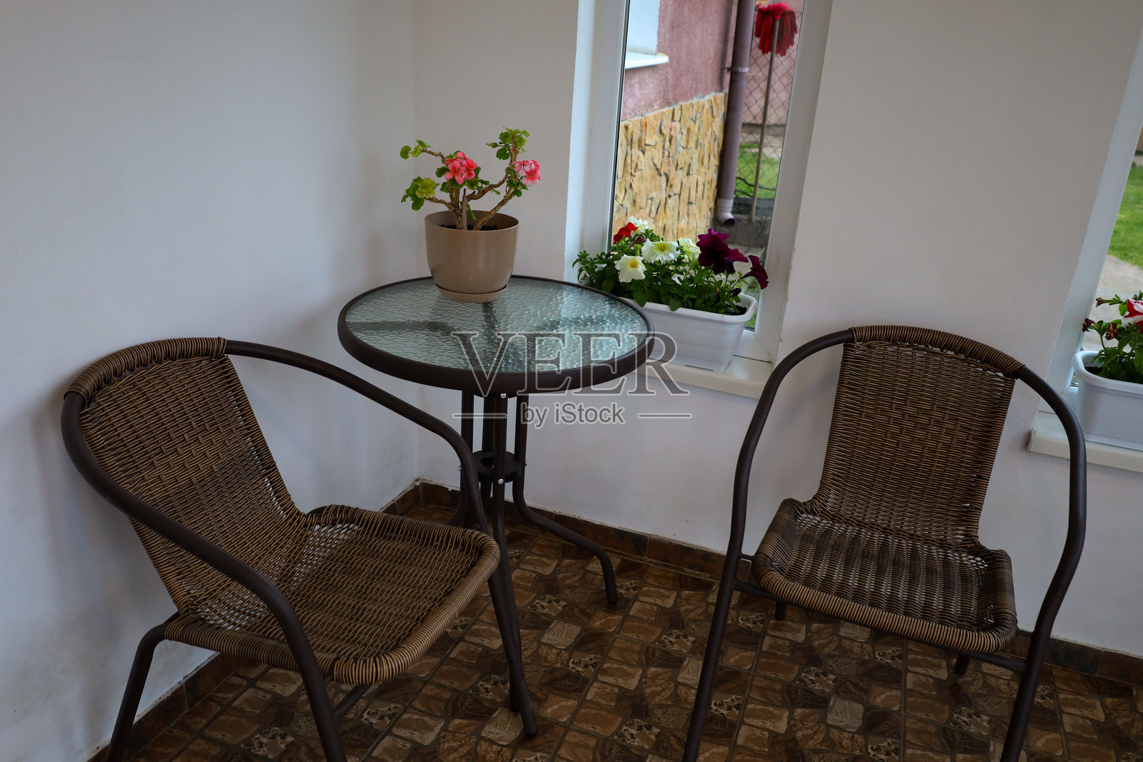 一个舒适的角落，配有藤椅和玻璃桌，装饰着花盆。这是一个理想的放松和享受时光的地方。明亮的房间营造出宁静和家庭舒适的氛围。照片摄影图片