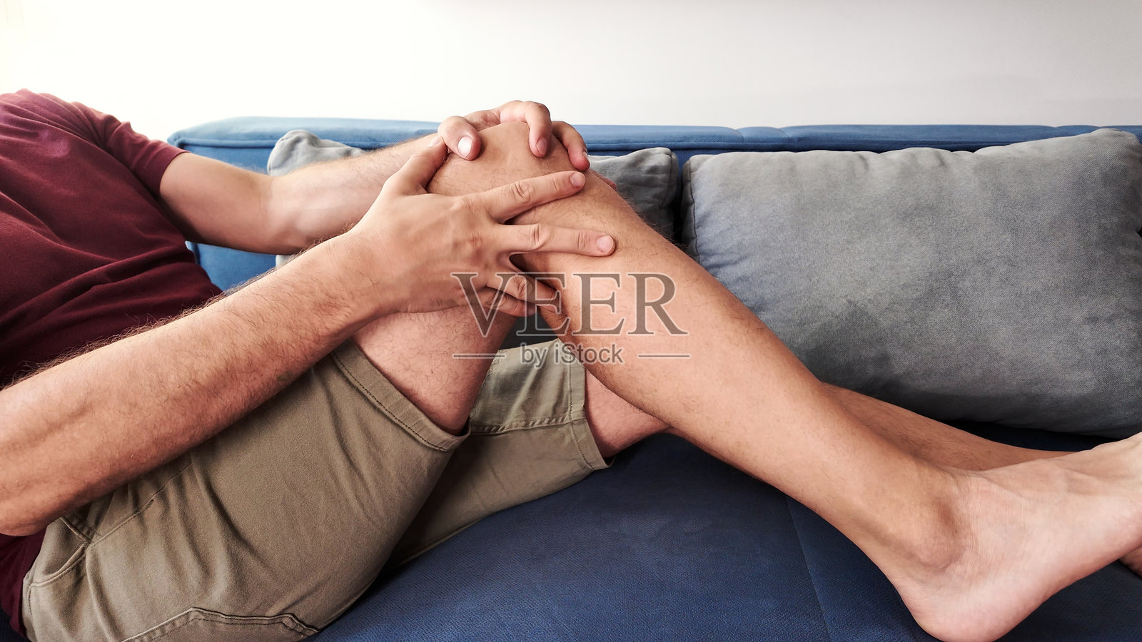 在家中感到膝盖和腿部疼痛的男人。照片摄影图片