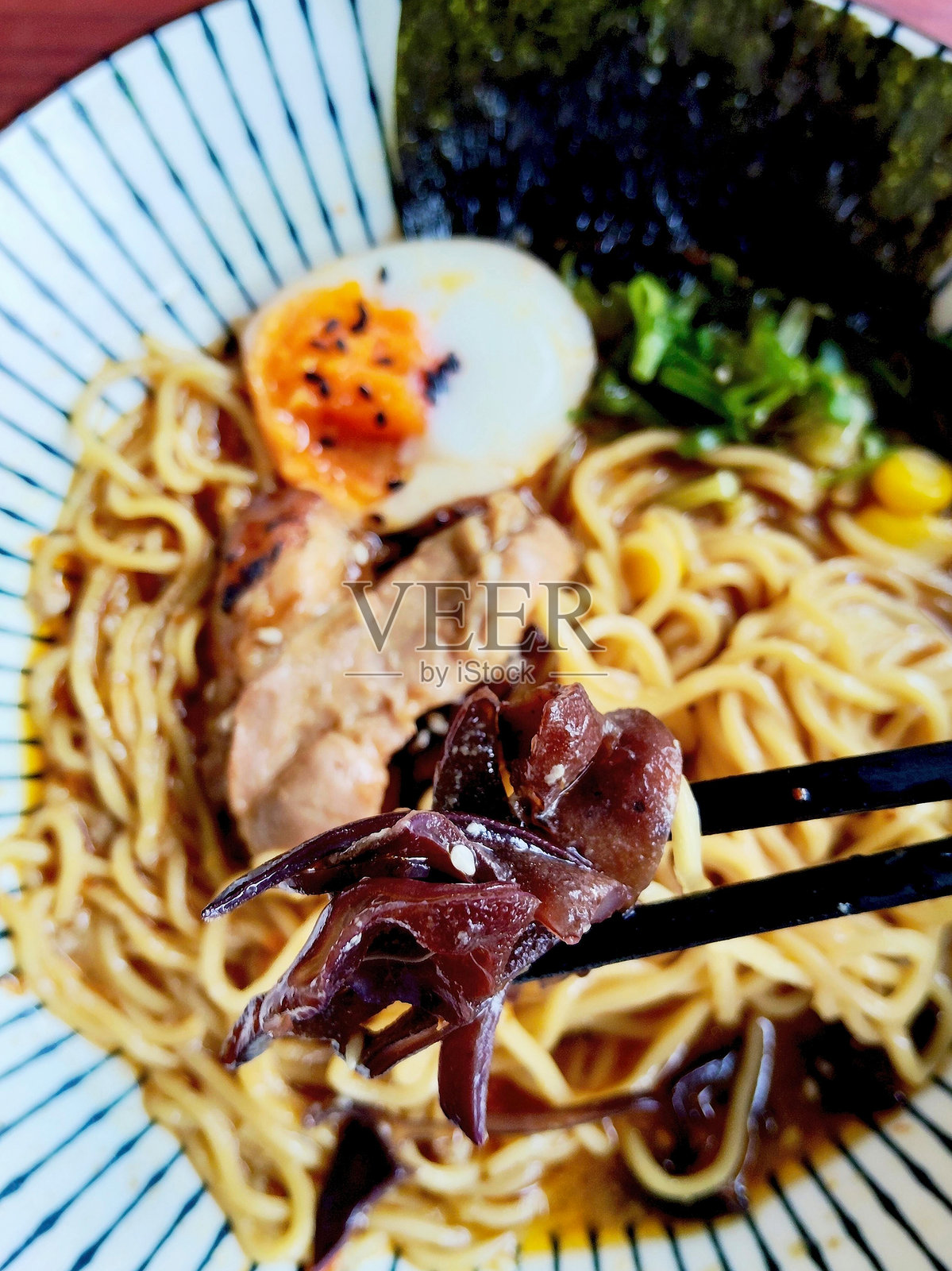 一只手用筷子夹起一朵多汁的蘑菇照片摄影图片