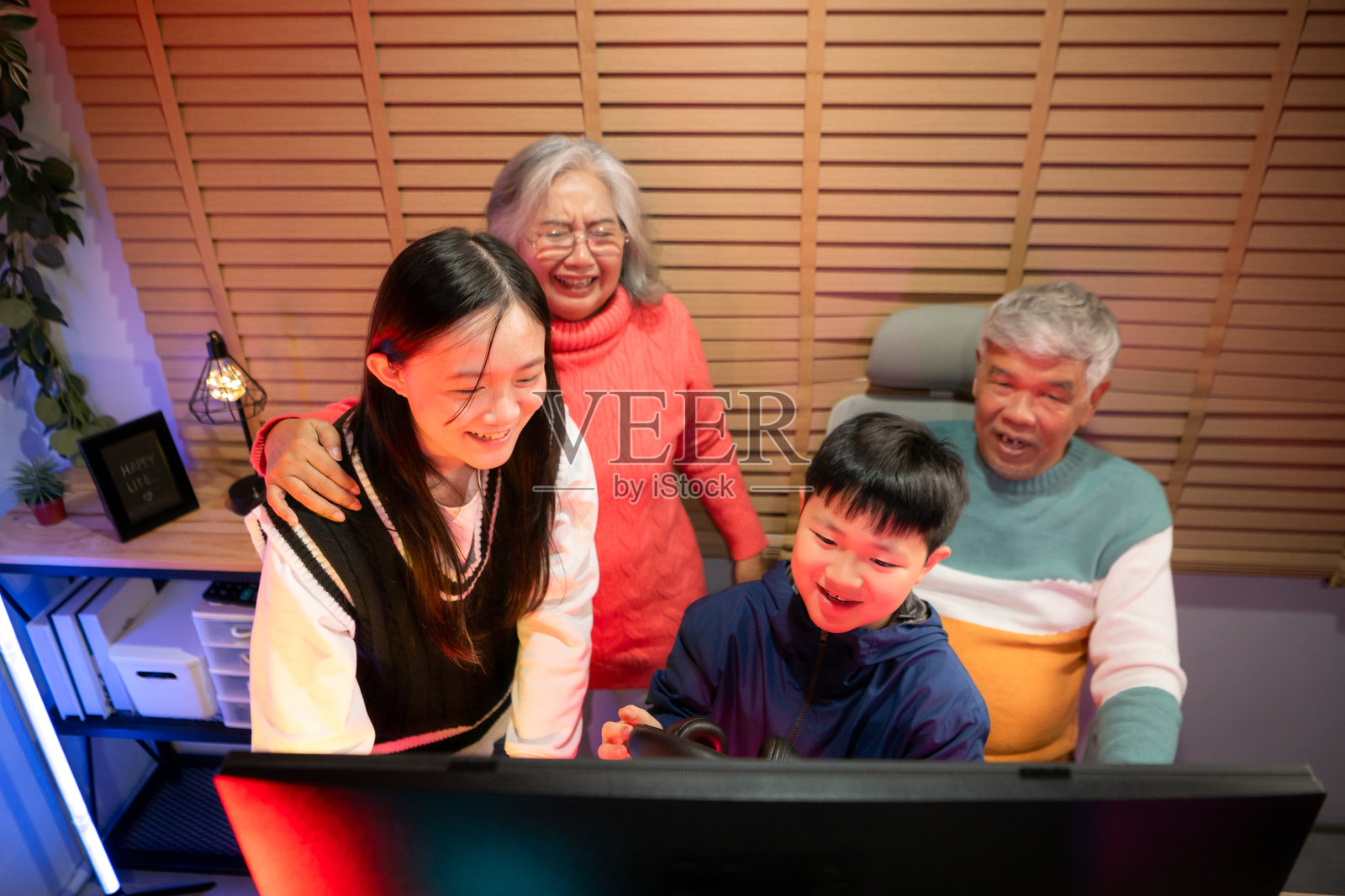 快乐的祖父母在霓虹灯照亮的房间里与孙子孙女们玩游戏照片摄影图片