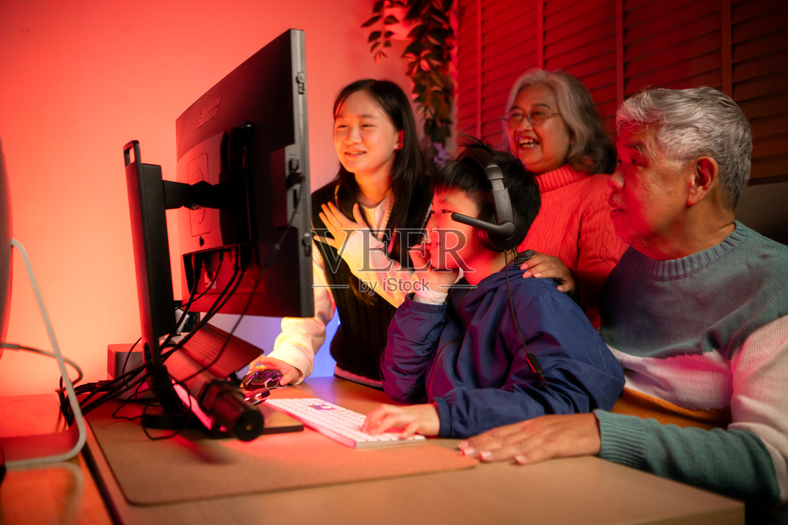 快乐的祖父母在霓虹灯照亮的房间里与孙子孙女们玩游戏照片摄影图片