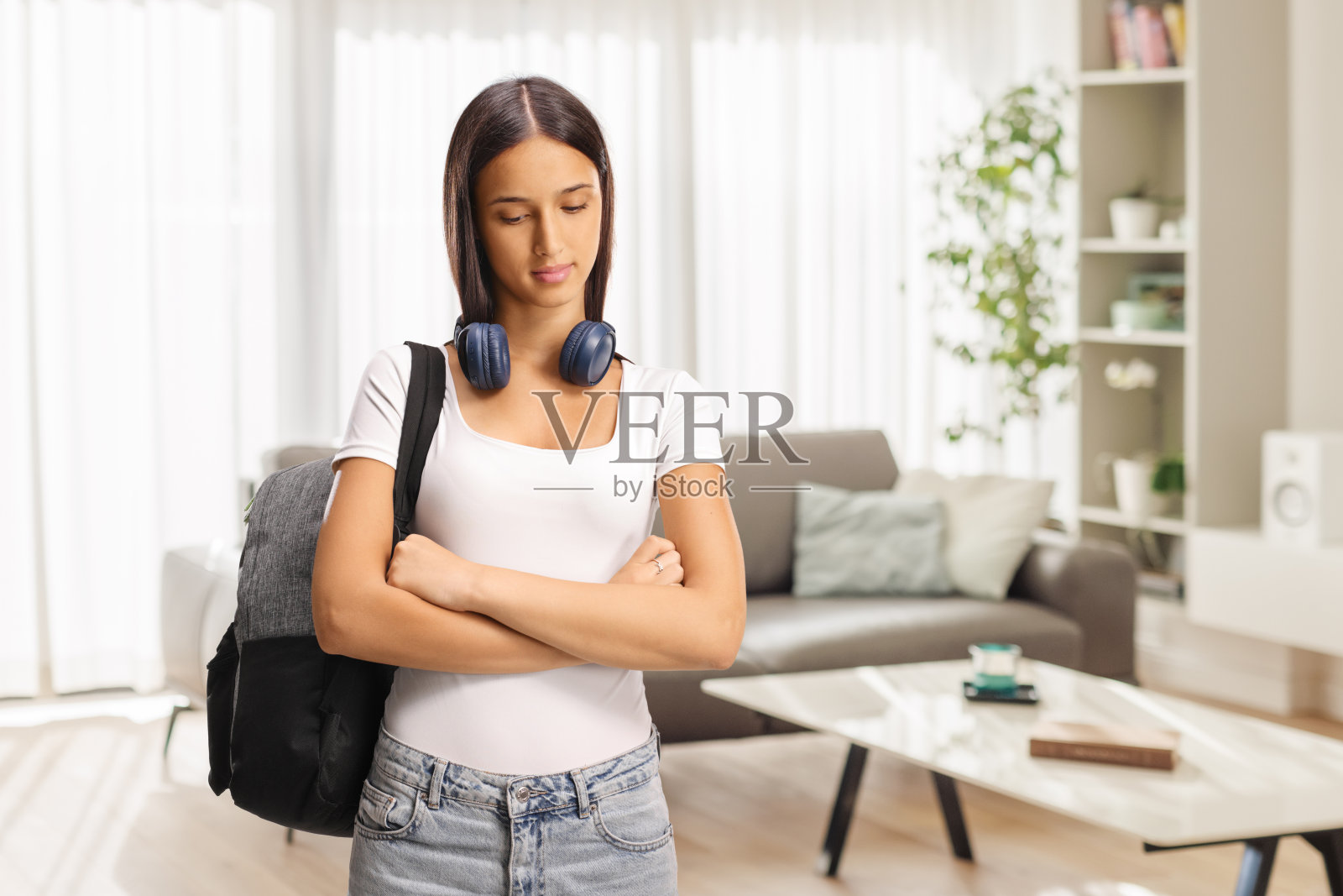 沉思的女青少年，脖子上挂着耳机照片摄影图片