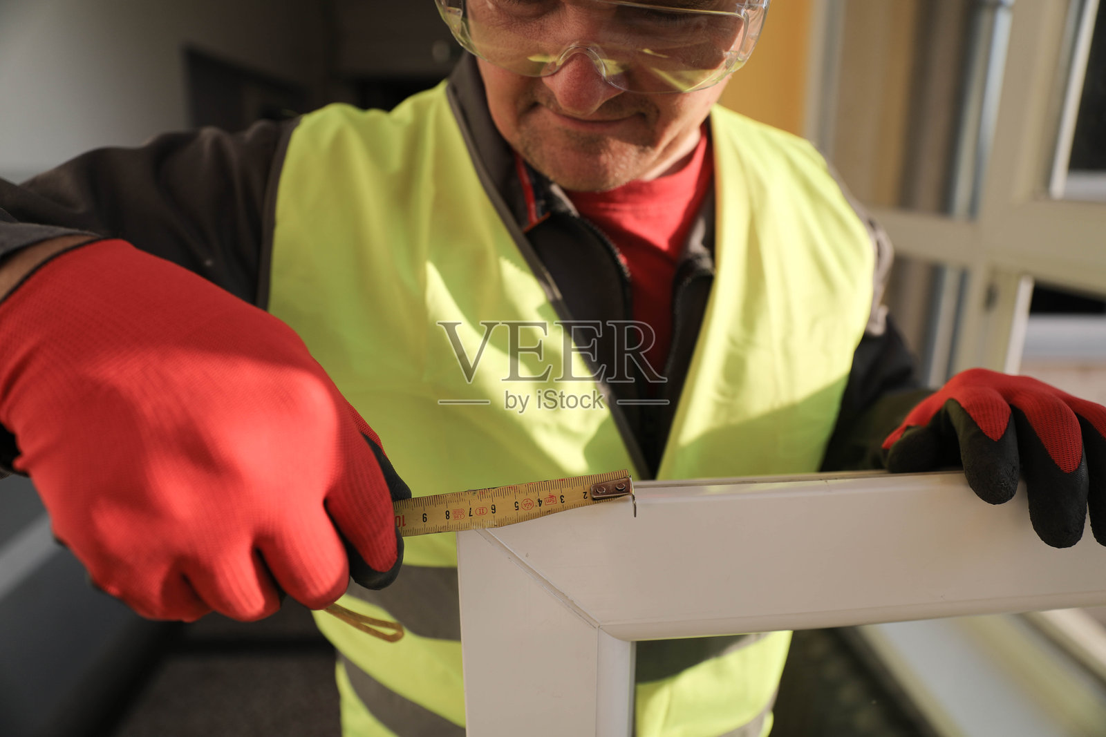 穿着防护装备的老年建筑工人在测量窗户结构照片摄影图片