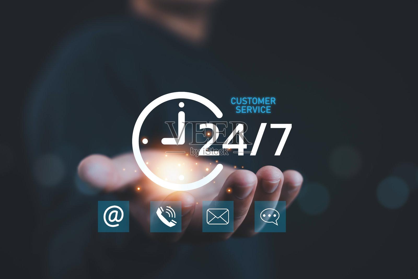 手握发光的24/7客户服务图标，包含电子邮件、电话和聊天符号，代表在线支持、商业协助、沟通、客户关怀和全天候服务解决方案。照片摄影图片