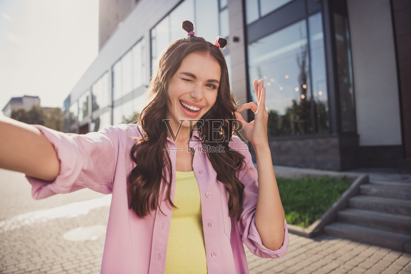 迷人的快乐波浪卷发女孩的自拍，旅行中做出“好”的手势，眨眼享受户外新鲜空气的乐趣照片摄影图片