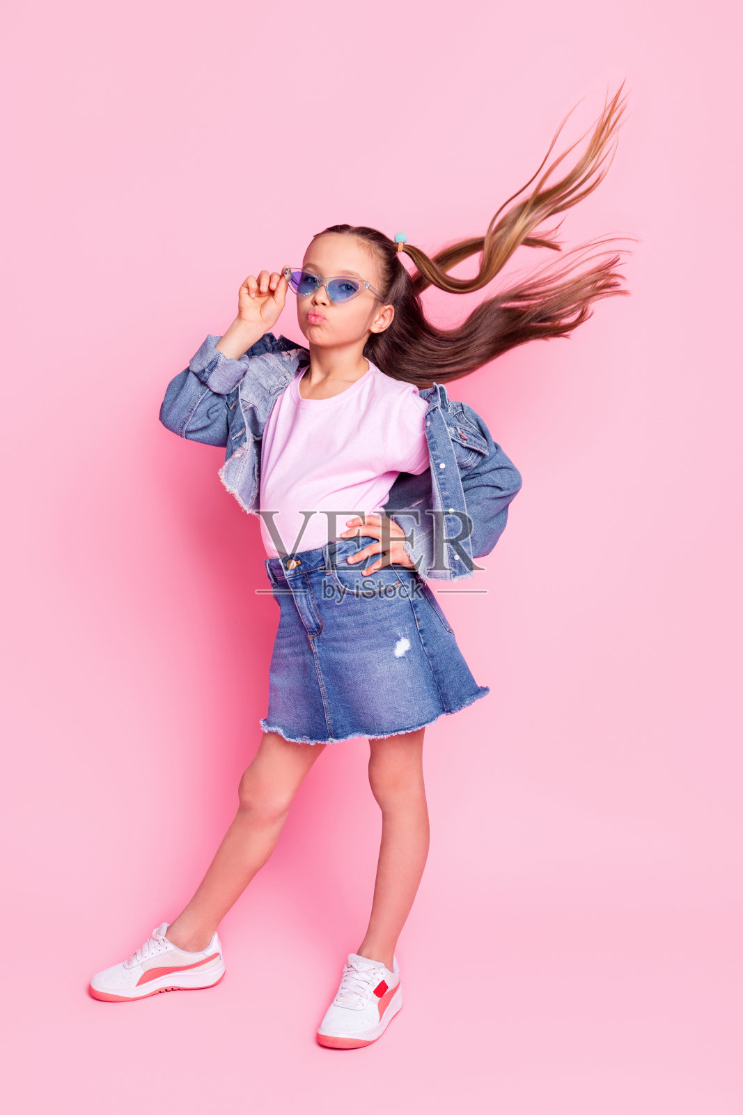 全身竖版照片，阳光开朗的女孩穿着牛仔裤，背景为粉色。照片摄影图片