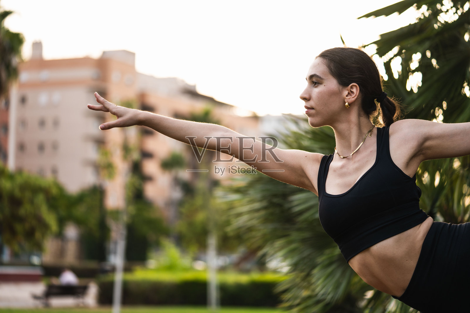 年轻女性在城市公园练习瑜伽战士姿势照片摄影图片