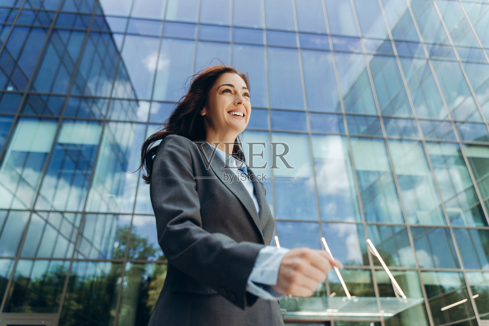 快乐的女商人在现代办公大楼附近散步照片摄影图片