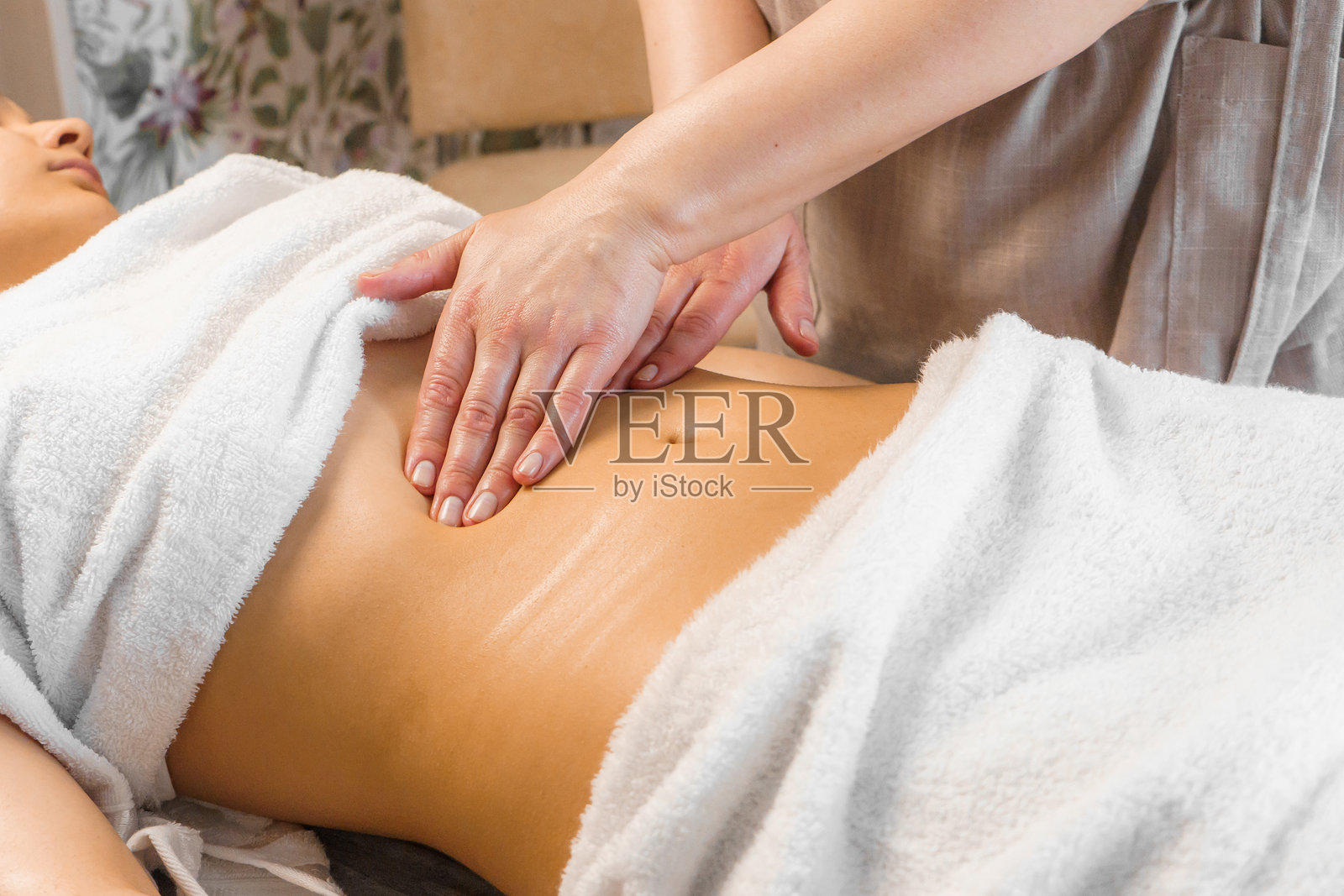 苗条年轻女性在水疗沙龙接受腹部按摩。照片摄影图片