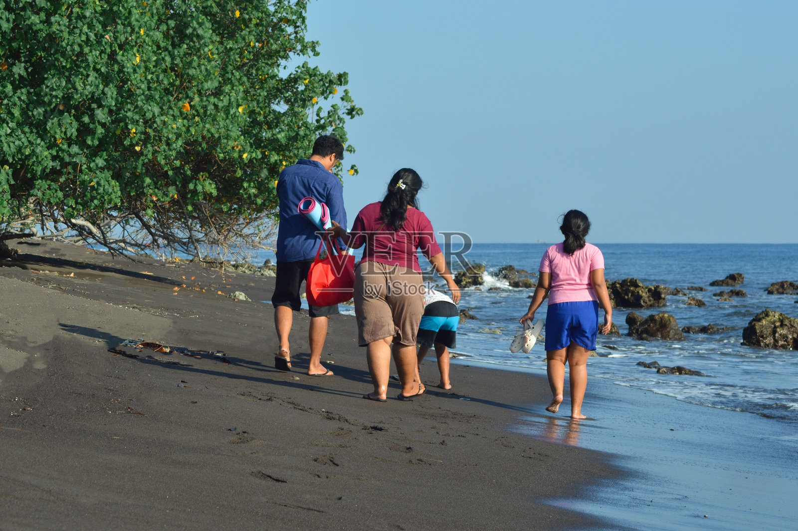 一家人在海滩上悠闲地散步，探索海岸线的美景照片摄影图片