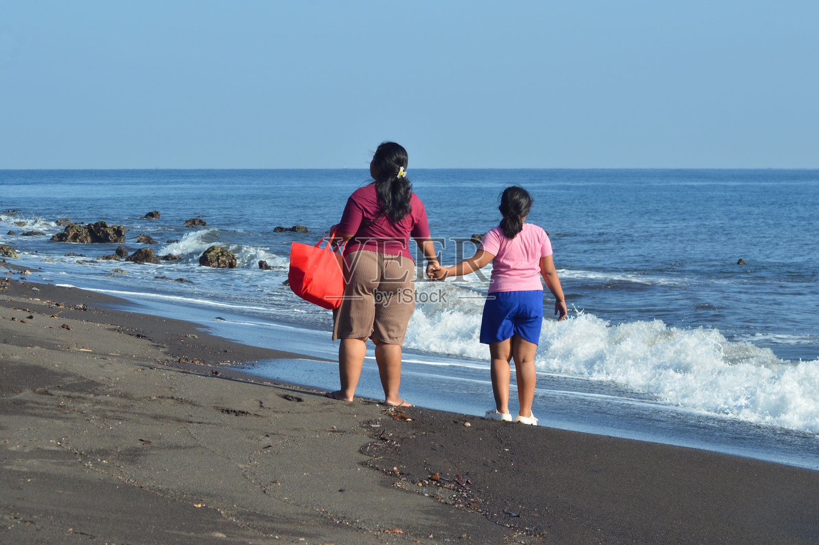 母女手牵手在海滩上散步照片摄影图片