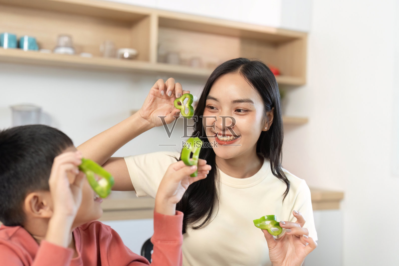 创意烹饪乐趣。母亲和儿子在玩绿色甜椒的形状。照片摄影图片