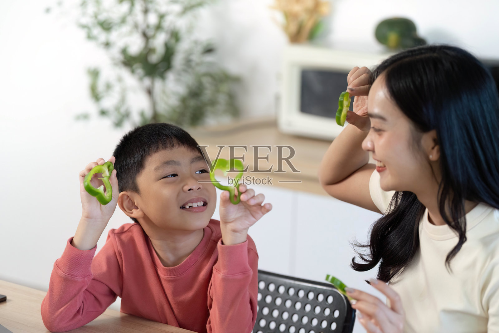 健康烹饪乐趣：母亲和儿子一起享受准备青椒的时光照片摄影图片